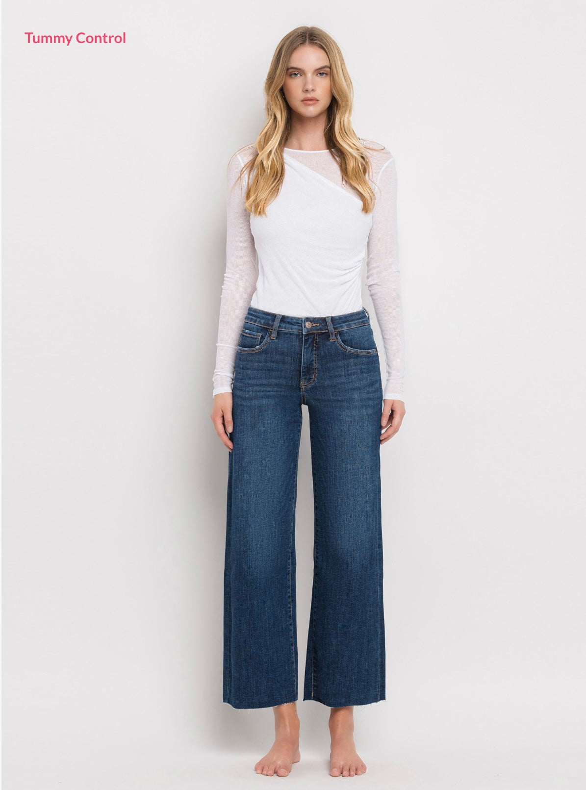 Woman wearing white long-sleeve top and blue wide-leg cropped denim jeans with tummy control feature