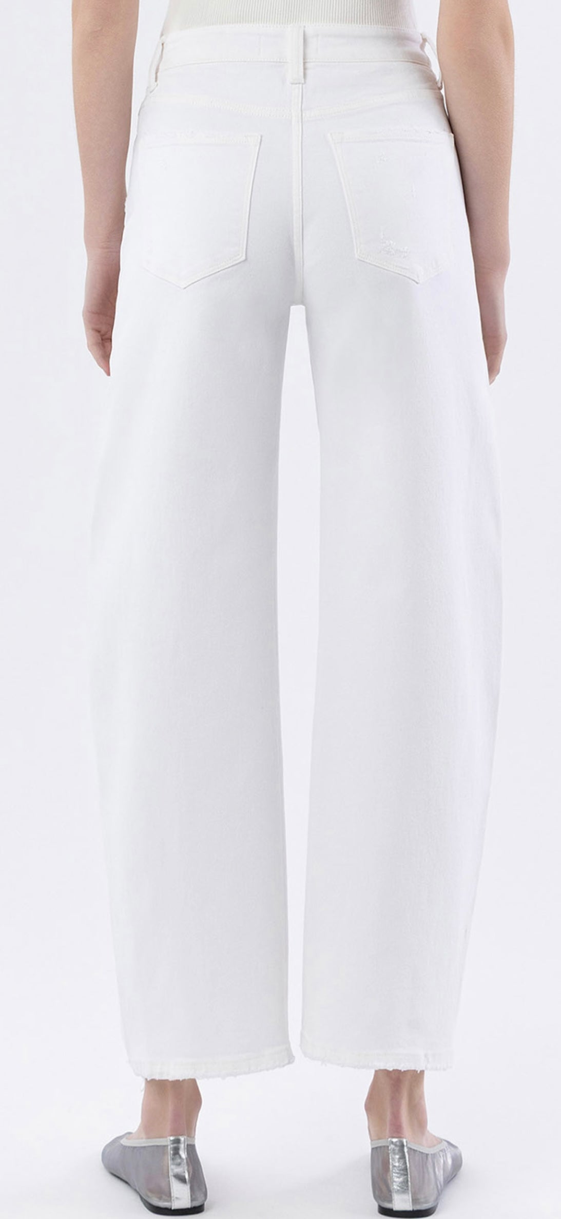 Back view of white wide-leg barrel jeans with frayed hem and silver metallic shoes