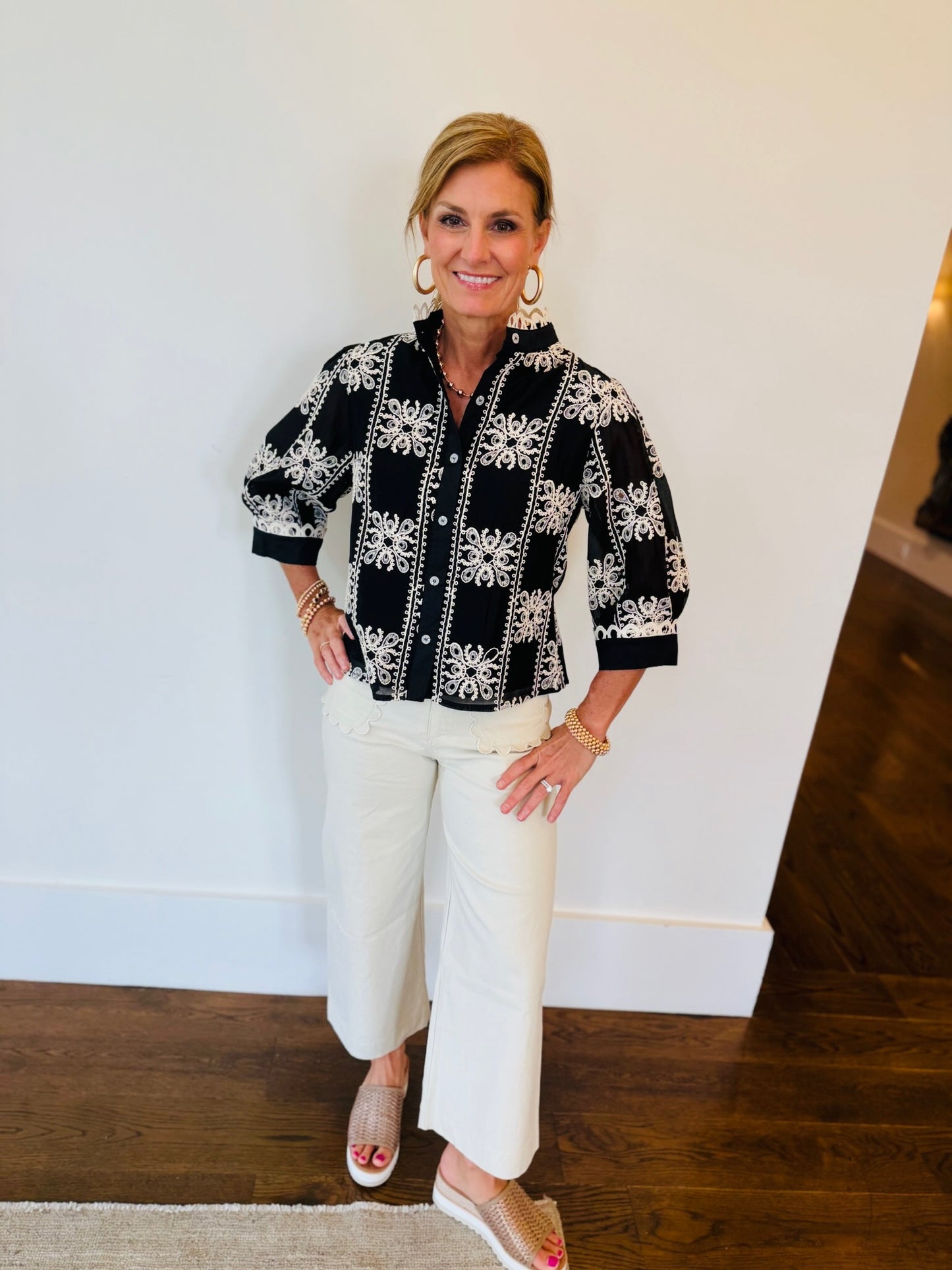 Model wearing black Harmony Top with white embroidered floral pattern, three-quarter puff sleeves, and button front.