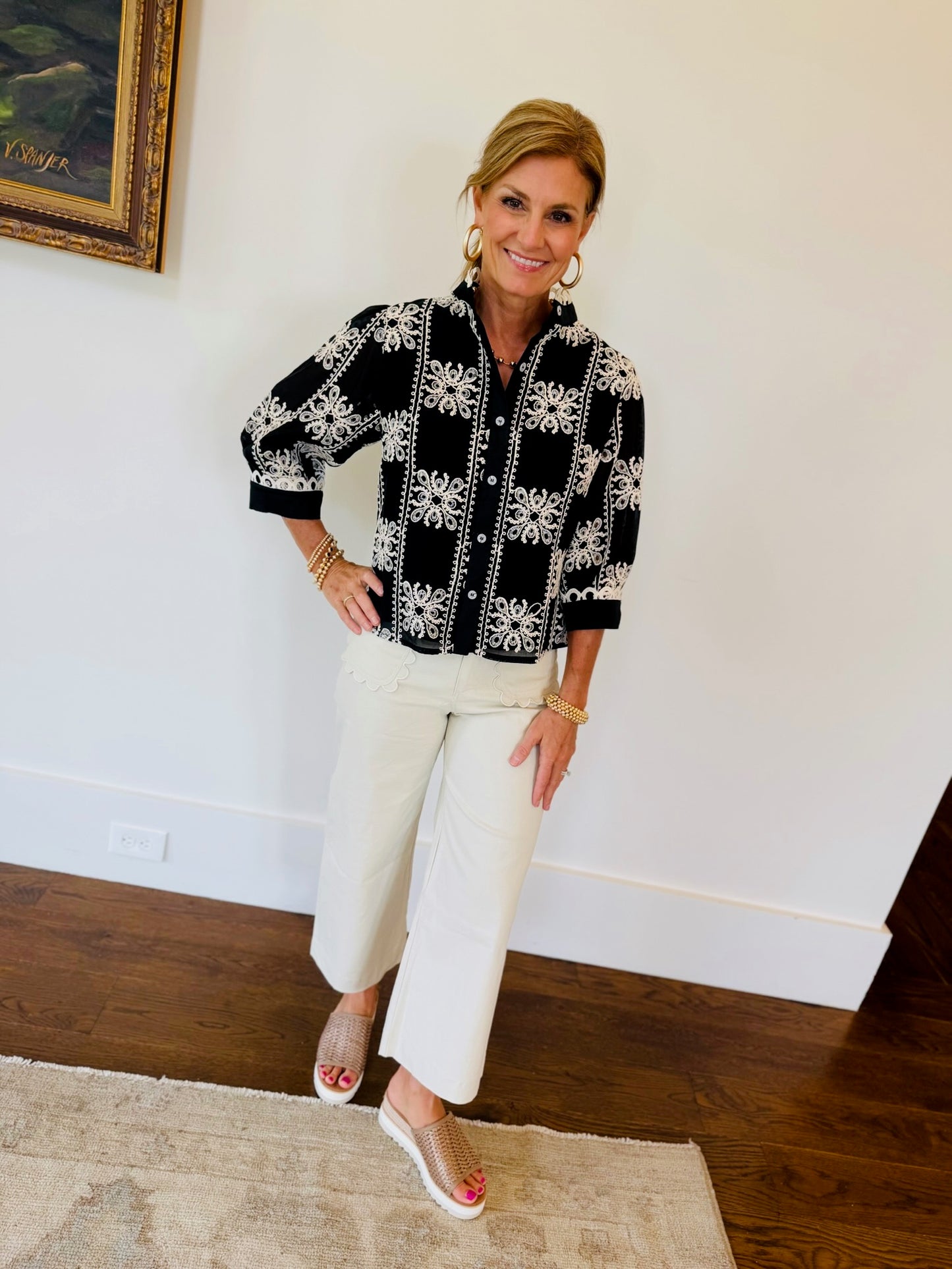 Model wearing black Harmony Top with white floral embroidery, paired with cream cropped pants and sandals.