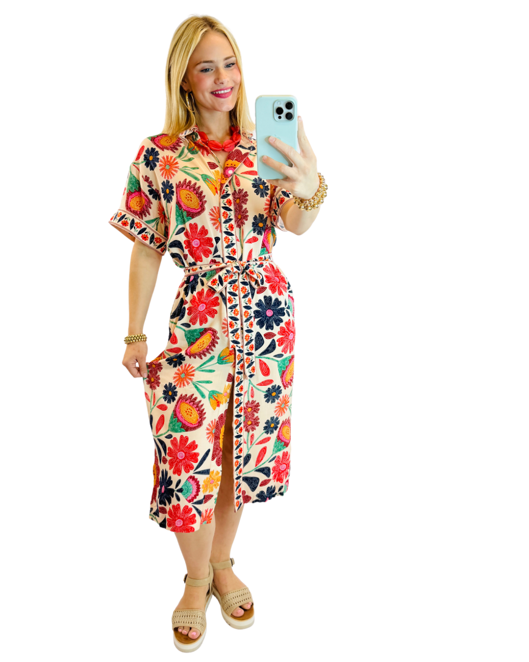 Woman wearing colorful floral midi dress with short sleeves, belt, and button-front closure while taking mirror selfie