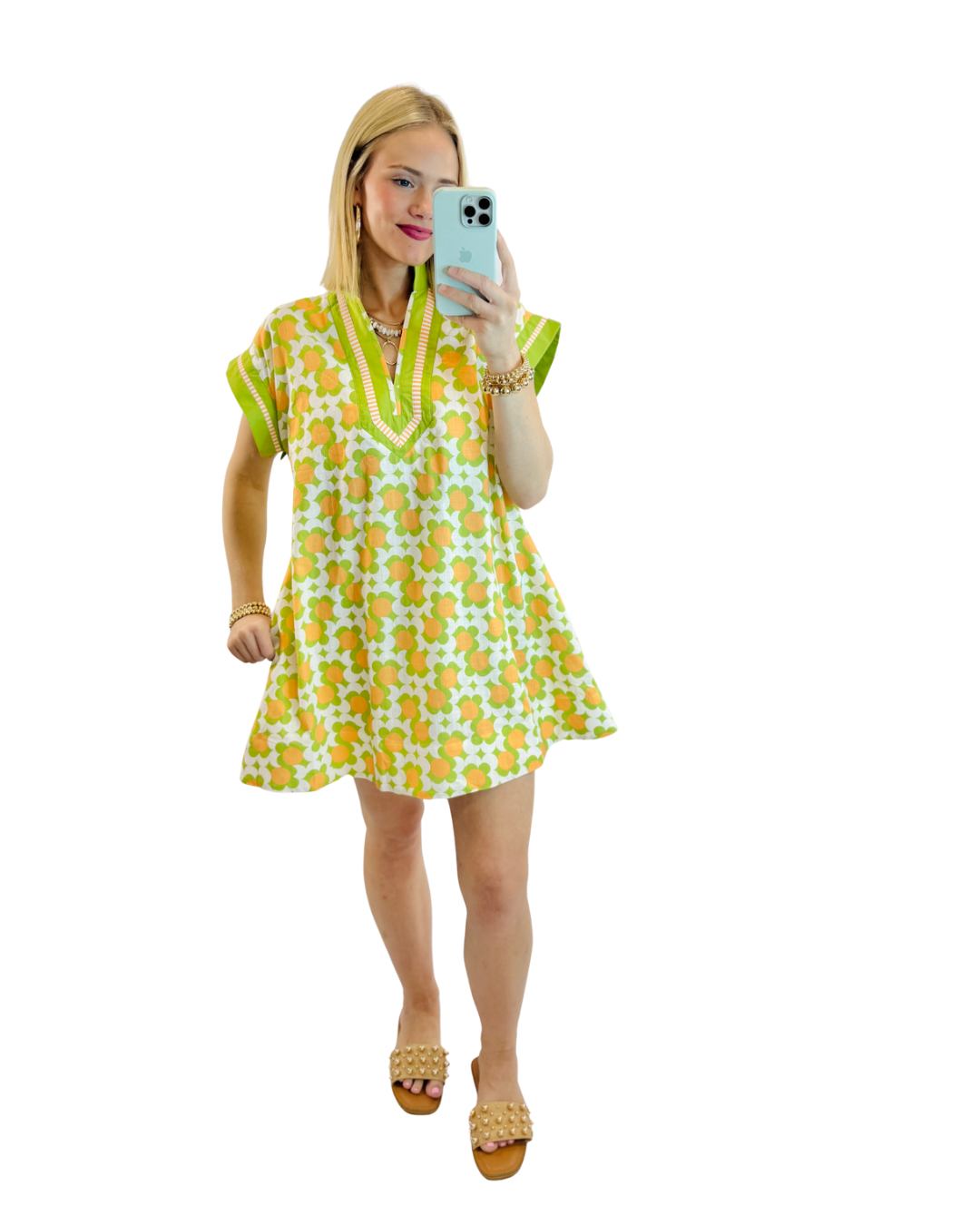 Woman wearing green and orange floral print Dora dress with short sleeves and v-neckline, taking mirror selfie.