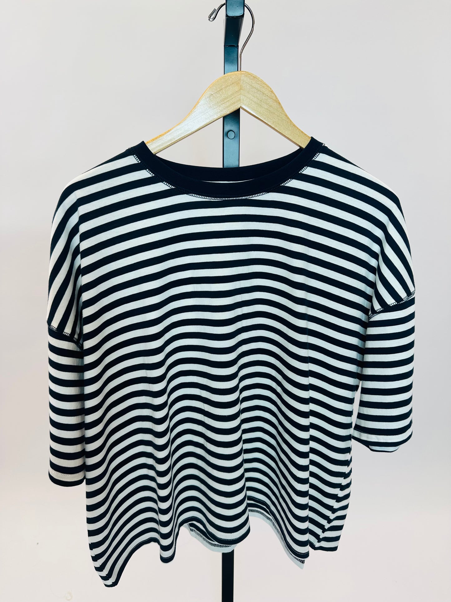 Navy and white striped oversized t-shirt with three-quarter sleeves hanging on wooden hanger