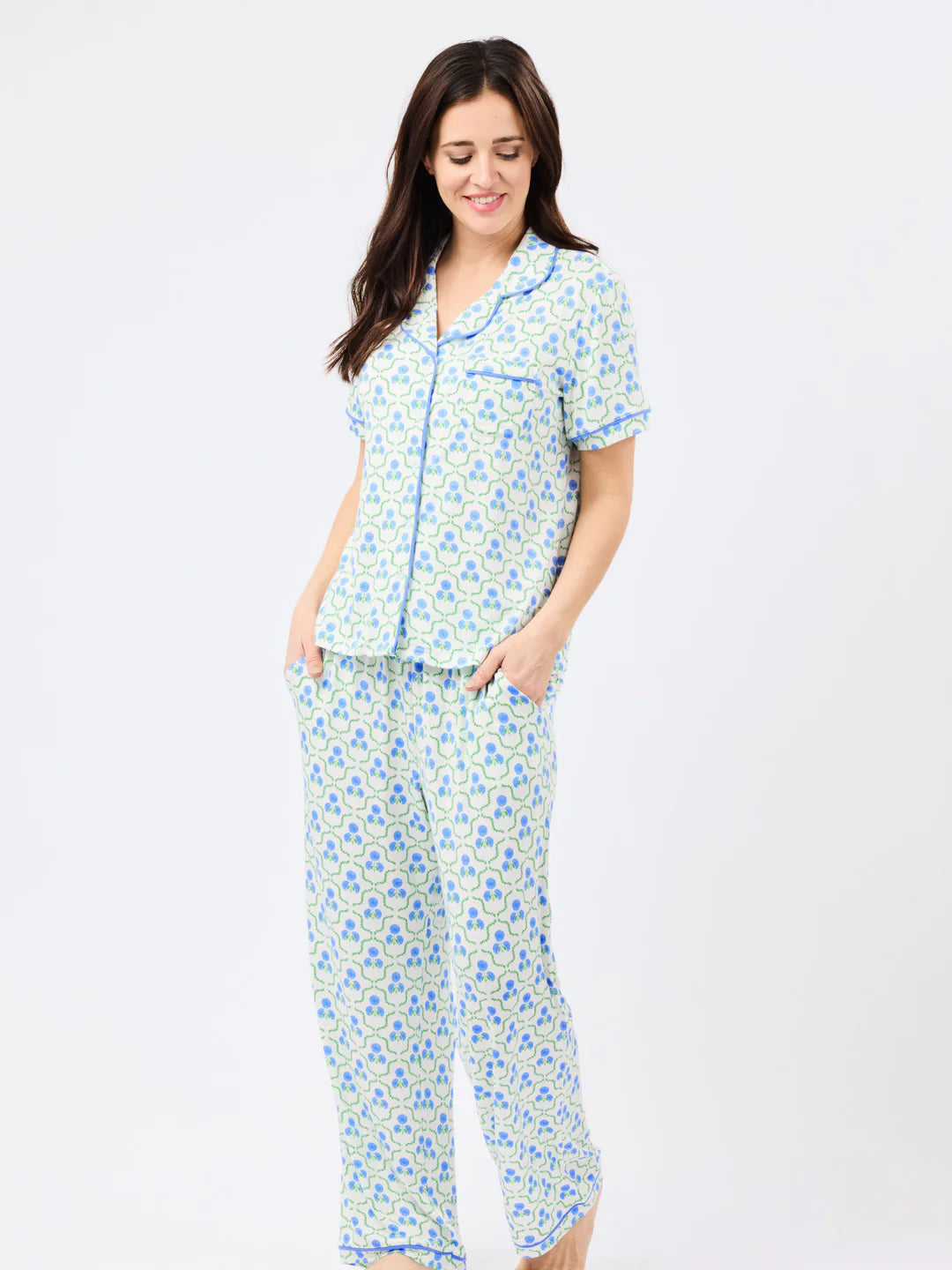 Woman wearing blue and green floral print pajama set with short-sleeve button-up top and matching pants