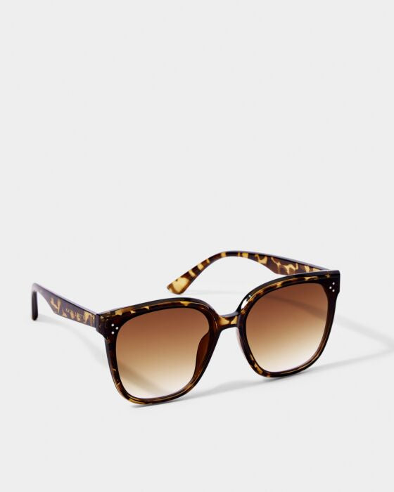 Brown tortoiseshell sunglasses with gradient lenses and decorative studs on frames against white background.