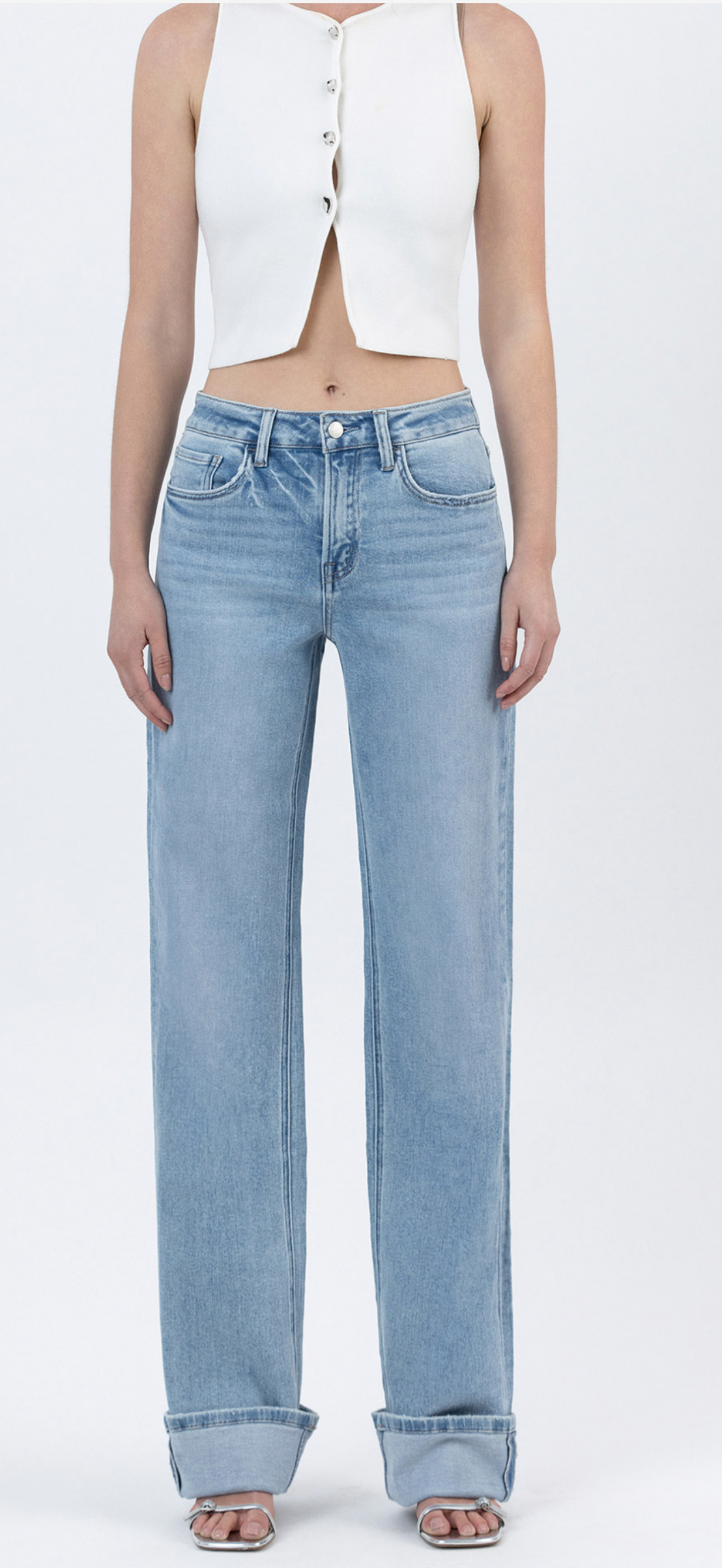 Light blue high-waisted straight leg jeans with rolled cuffs worn with white cropped button-up vest top.