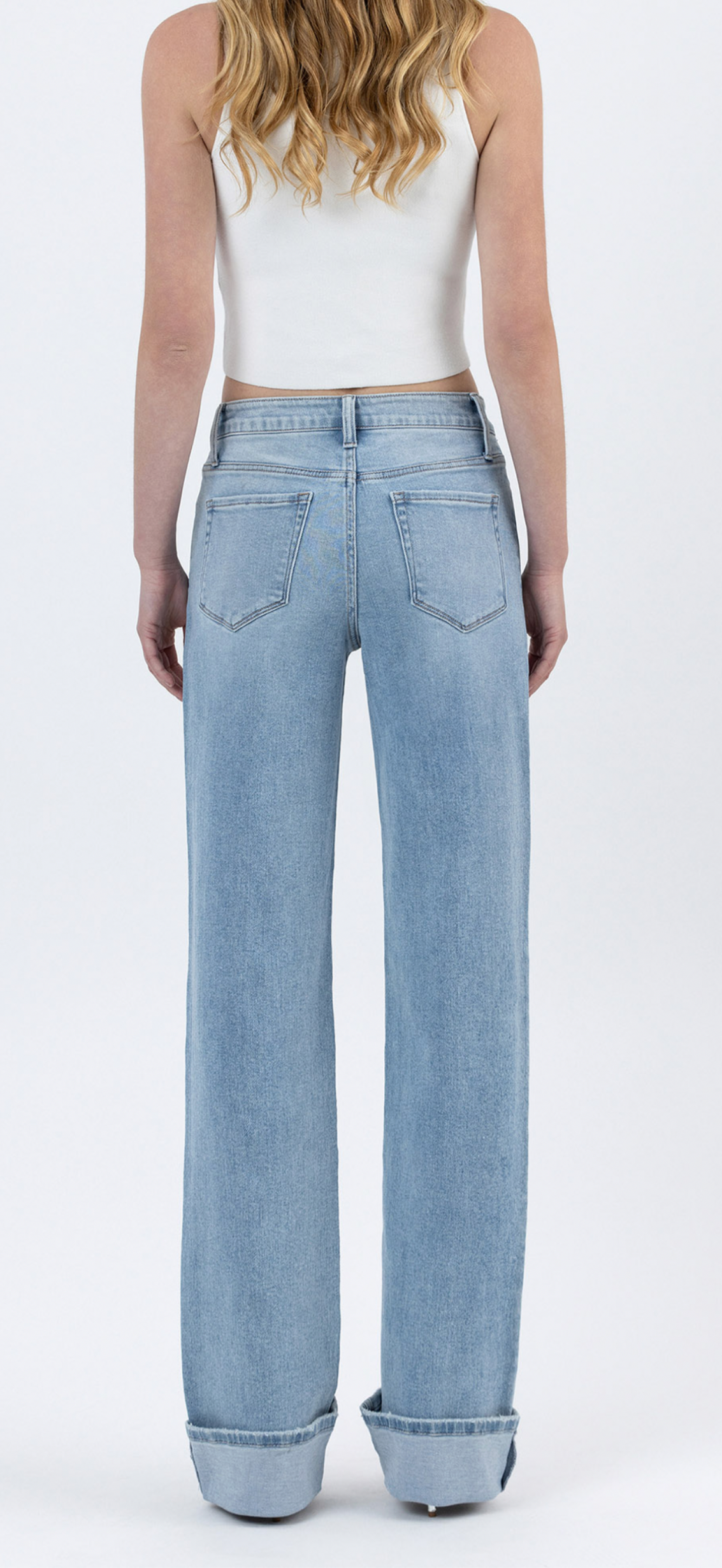 Woman wearing light blue wide-leg cuffed denim jeans with white crop top, shown from behind.