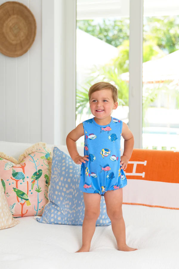Young child wearing blue fish-print pima cotton bubble romper, standing confidently with hands on hips.