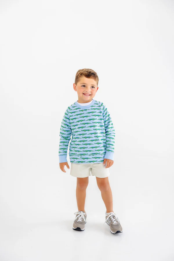 Young boy wearing striped blue and green long-sleeve shirt with white shorts and gray sneakers