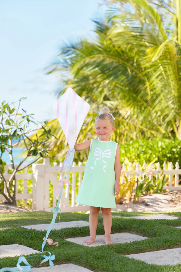 Young girl wearing mint green sleeveless dress with white bow applique, holding kite outdoors