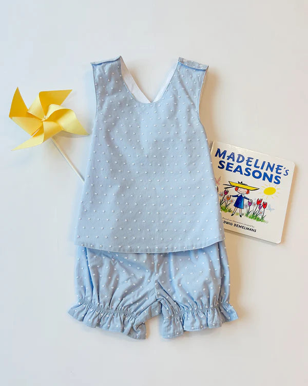 Light blue polka dot baby bloomer set with sleeveless top and ruffled shorts displayed with yellow pinwheel and children's...