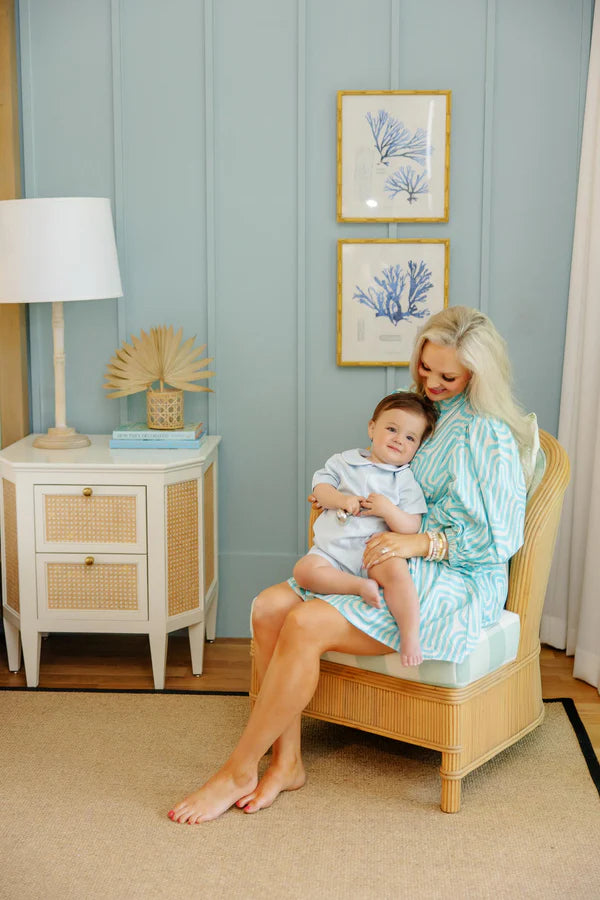Mother holding baby boy wearing light blue short sleeve pique jon jon romper in nursery