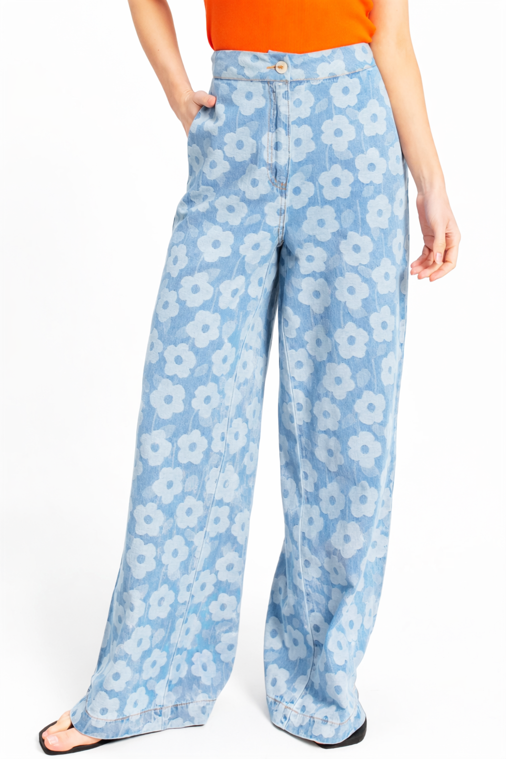 Light blue wide-leg denim pants with white daisy floral print, high-waisted with button closure.