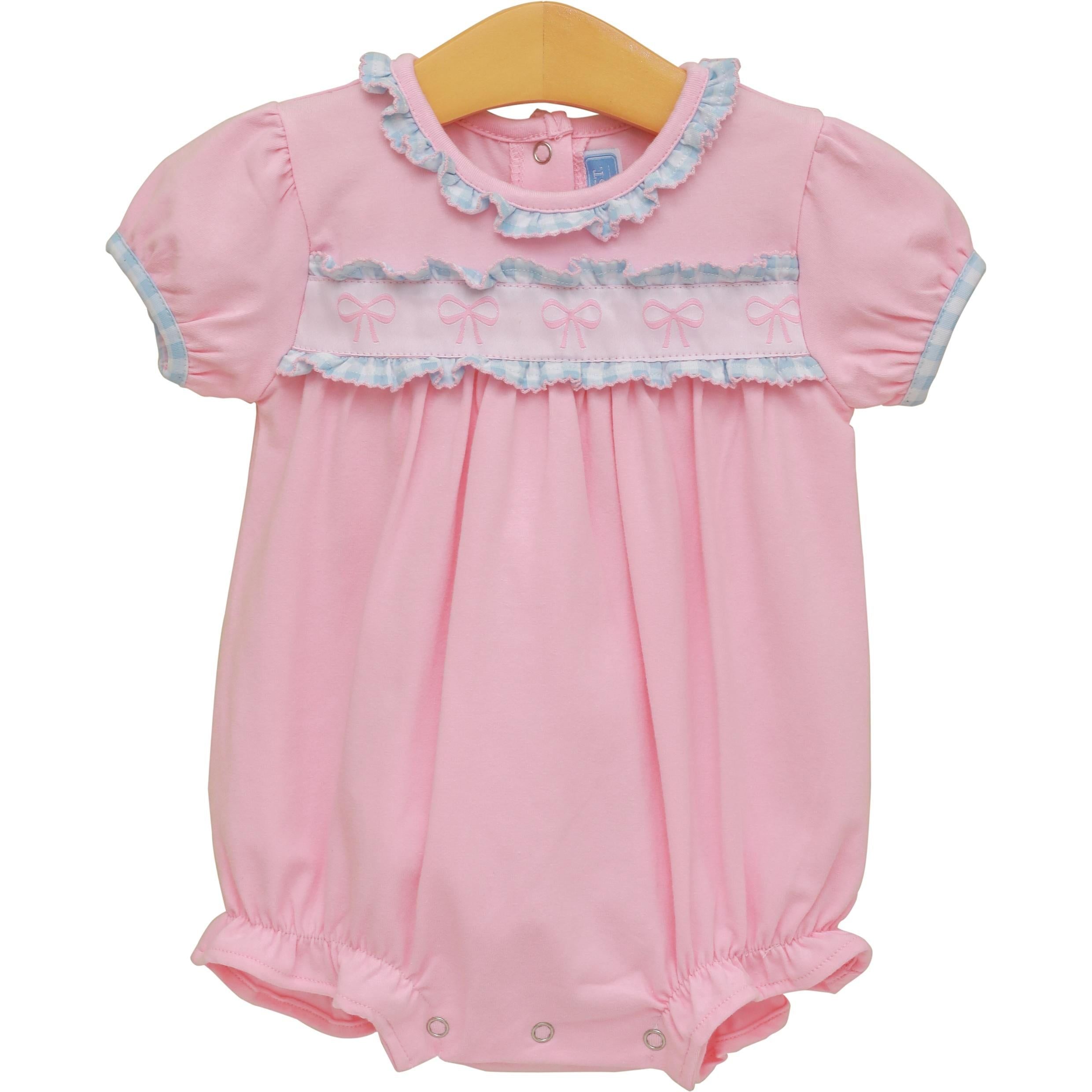 Pink baby bubble romper with blue ruffles, embroidered bows, and short sleeves on wooden hanger.
