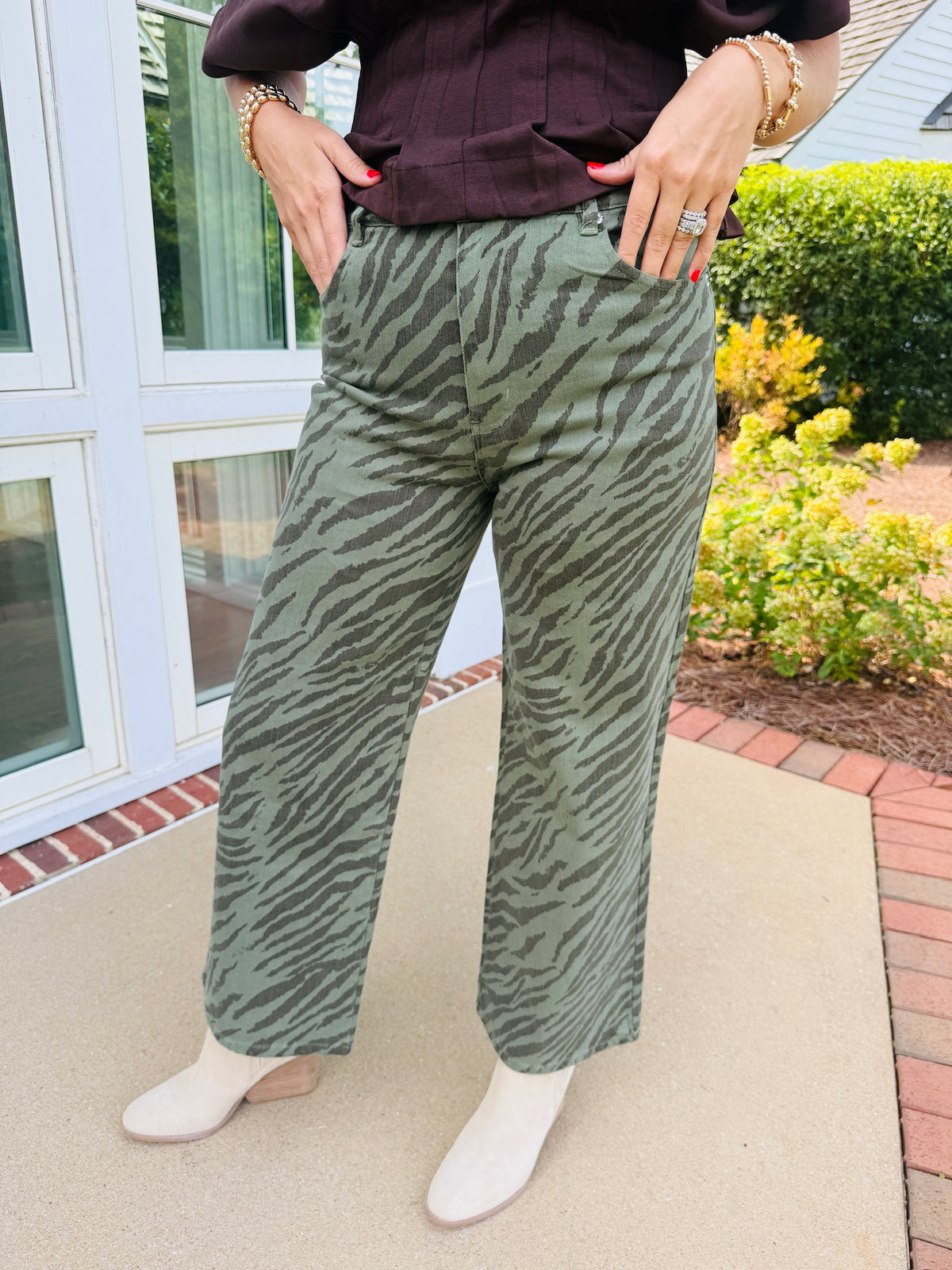 Close-up of the Josie olive zebra print cropped wide leg pants, showing front pockets and styled with cream ankle boots.