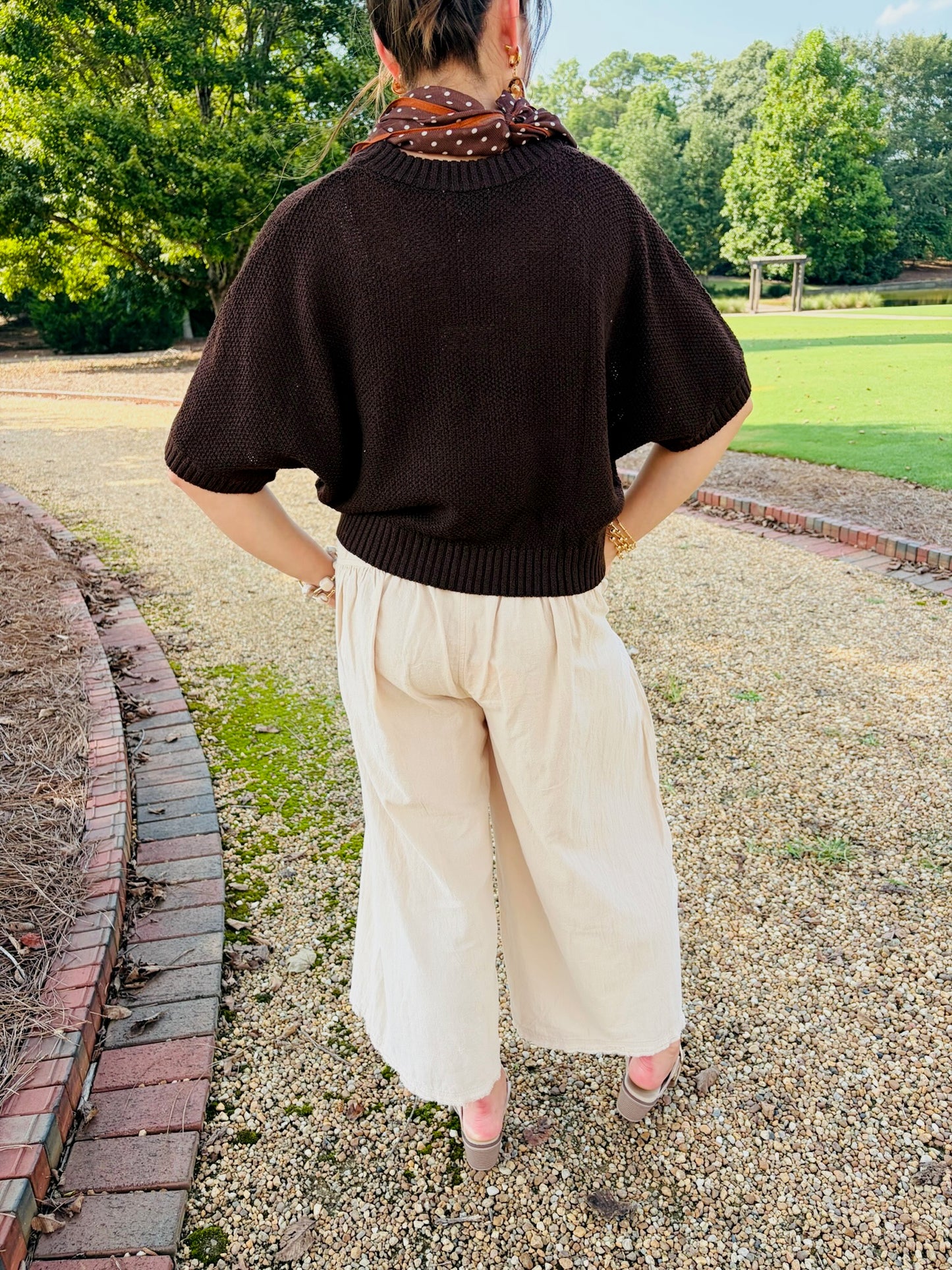 Back view of the Kaia brown short-sleeve knit top styled with cream pants