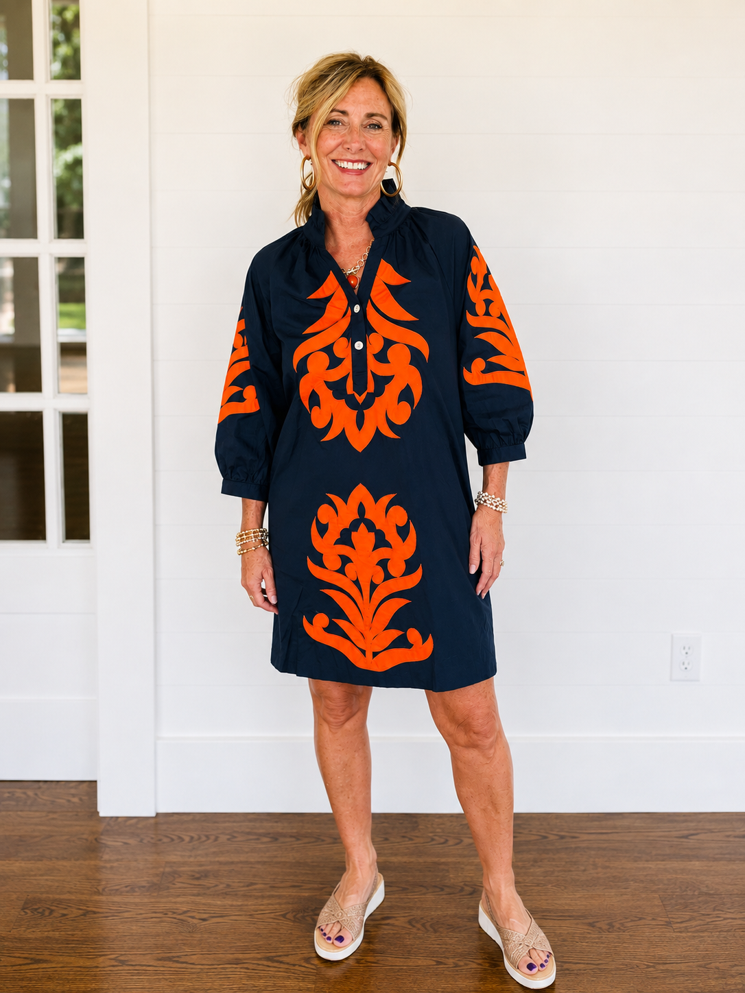 Bold burnt-orange appliqué medallions trail down the front, back, and full balloon sleeves of a crisp navy cotton shift, giving this easy silhouette a hand-finished, heirloom-embroidered look you won't find on a rack of basic tees and jeans.