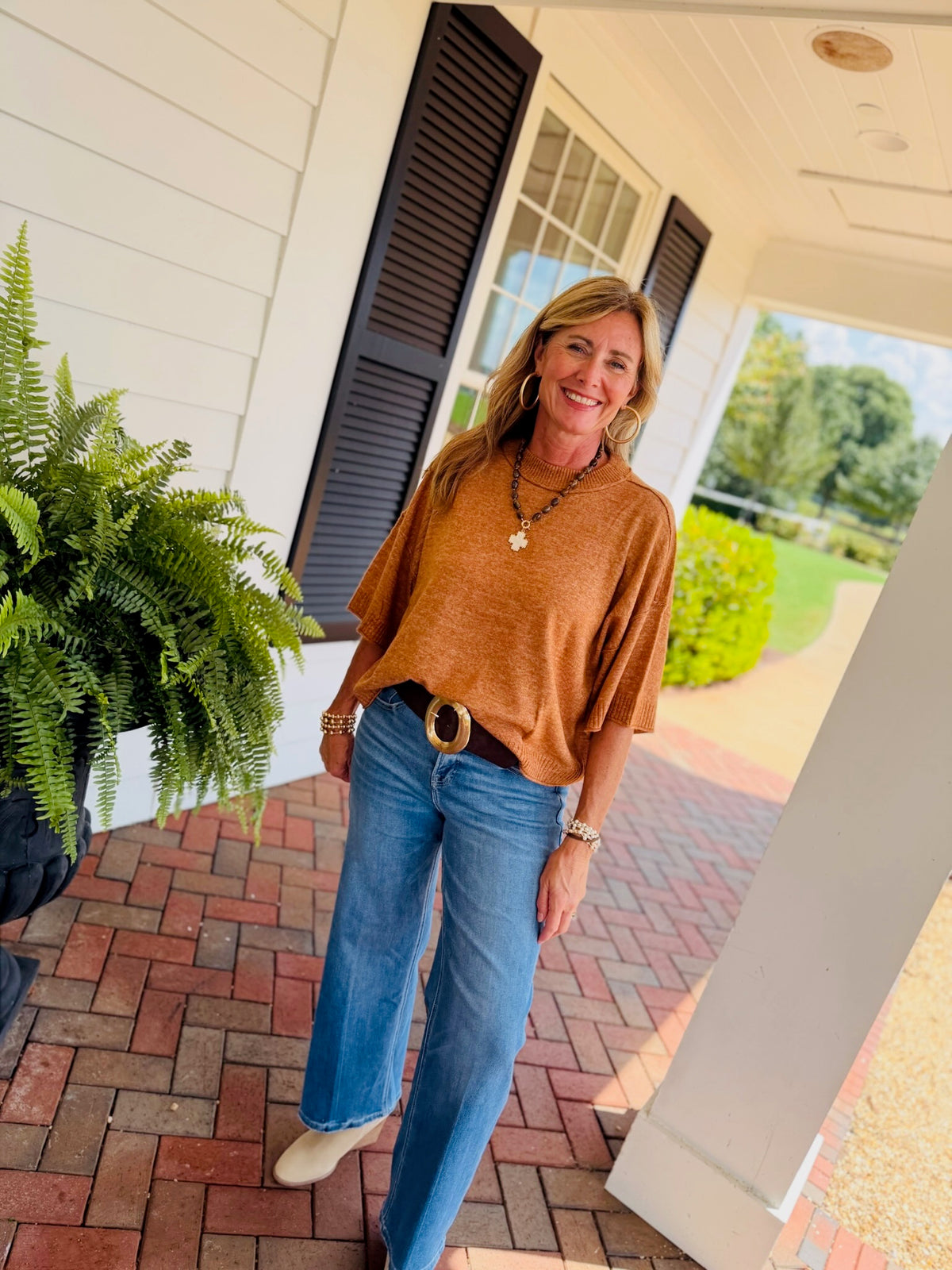 Mavis mocha short sleeve sweater top styled with wide leg blue jeans, a brown belt, and cream ankle boots.