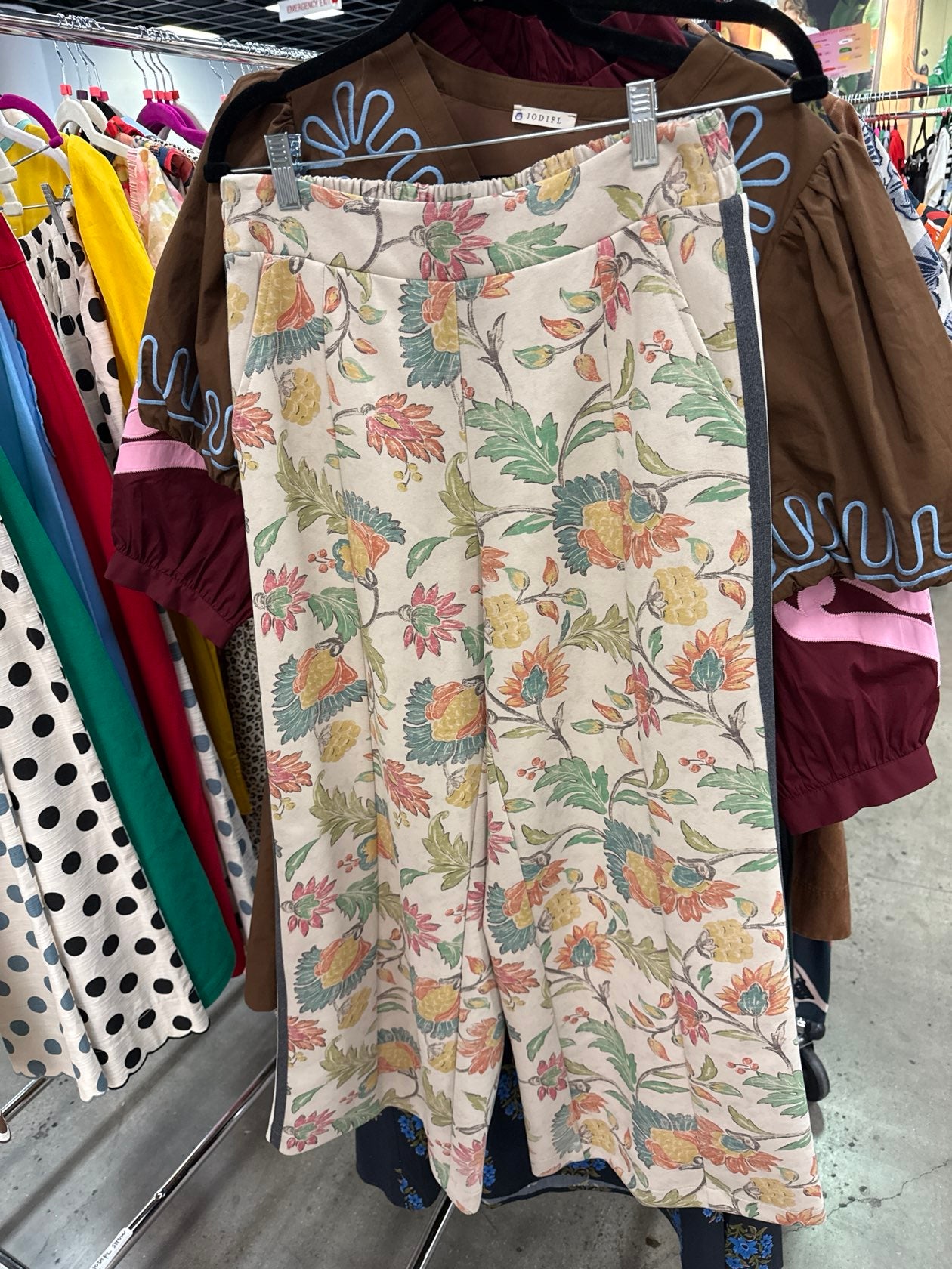 Floral print wide-leg culottes in oatmeal with multicolor botanical pattern, elastic waistband, hanging on rack.