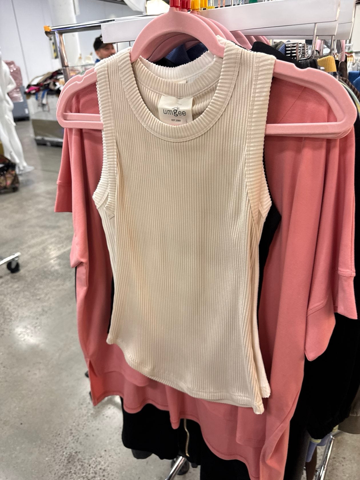 Umgee cream ribbed sleeveless tank top hanging on pink hanger in retail store.