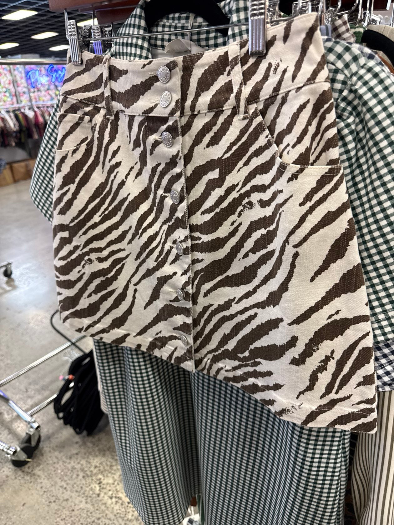 Jade Ecru zebra print mini skirt with silver button-front closure and side pockets.