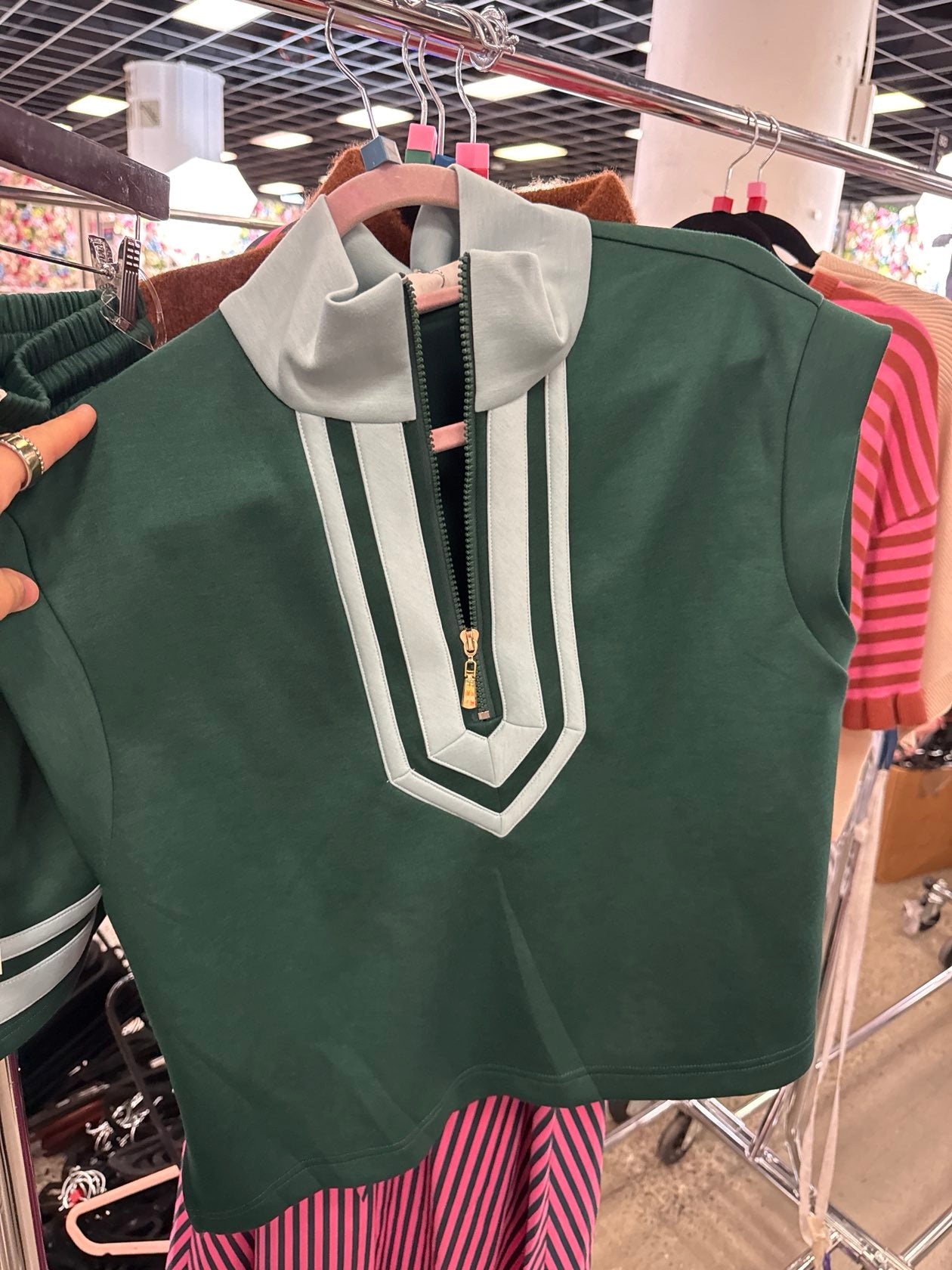 Sleeveless green zip-up crop top with light green contrast collar and geometric panel detailing.