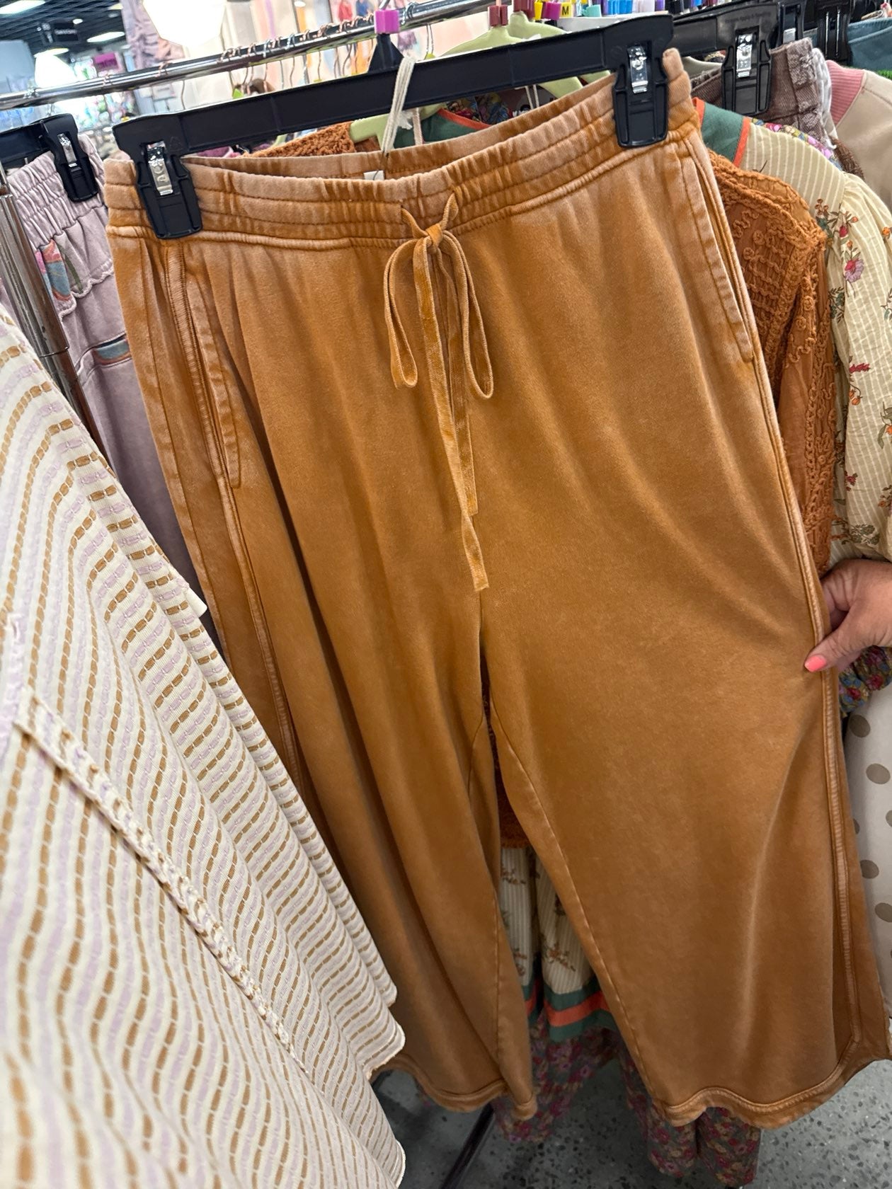 Camel brown velvet drawstring jogger pants with elastic waistband, hanging on retail rack.