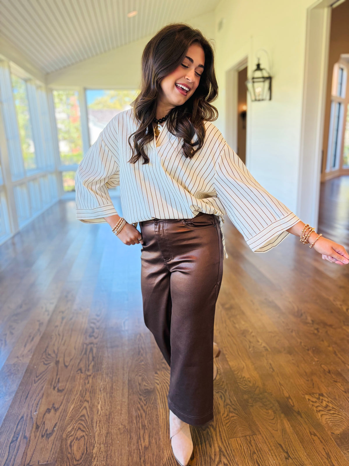 Lacey wearing the Ailany ivory striped drawstring blouse with brown trousers and neutral pointed-toe boots.