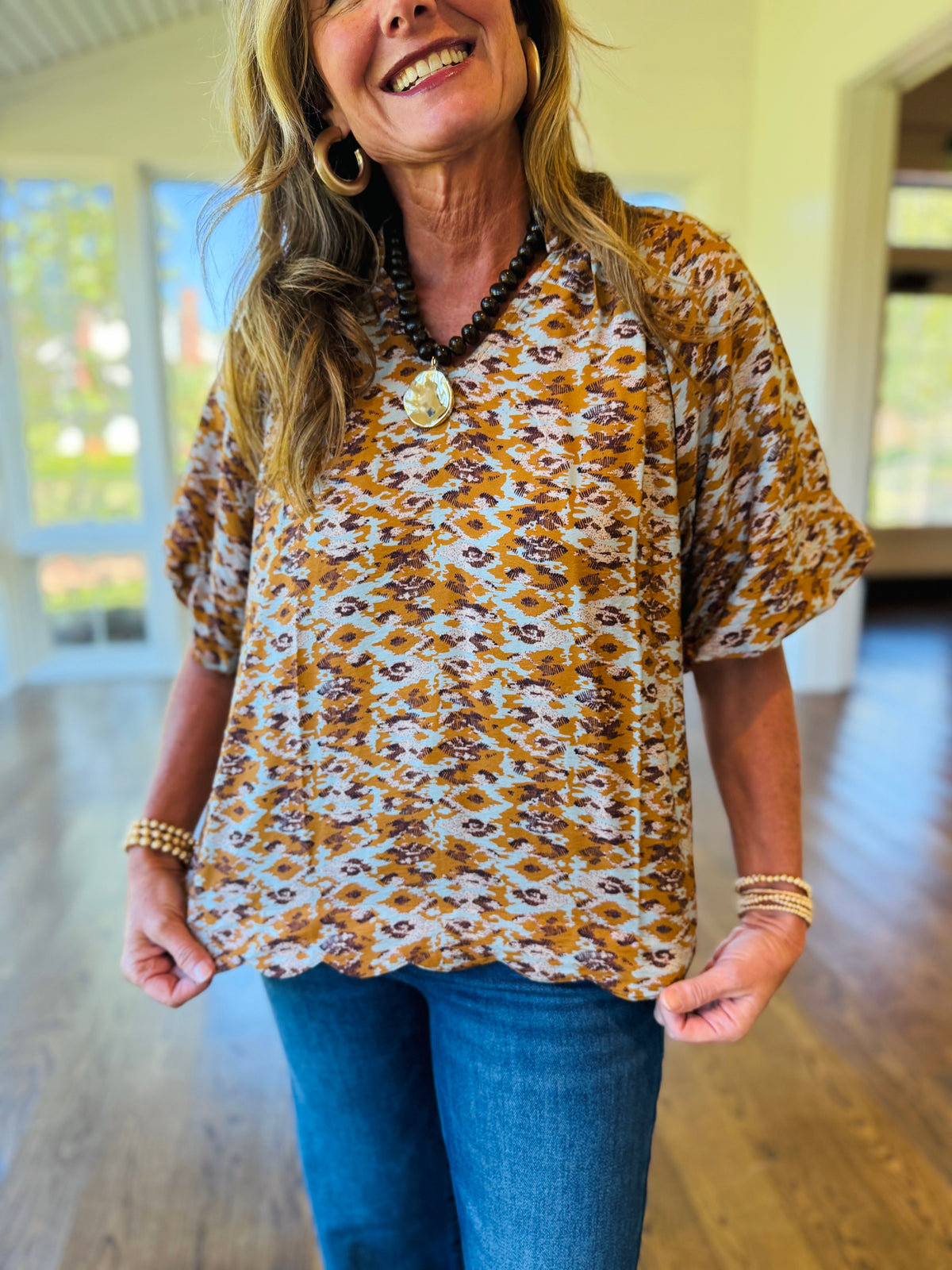Close-up of the Alana rust abstract print blouse showing its V-neckline, short puff sleeves with gathered cuffs and relaxed fit.