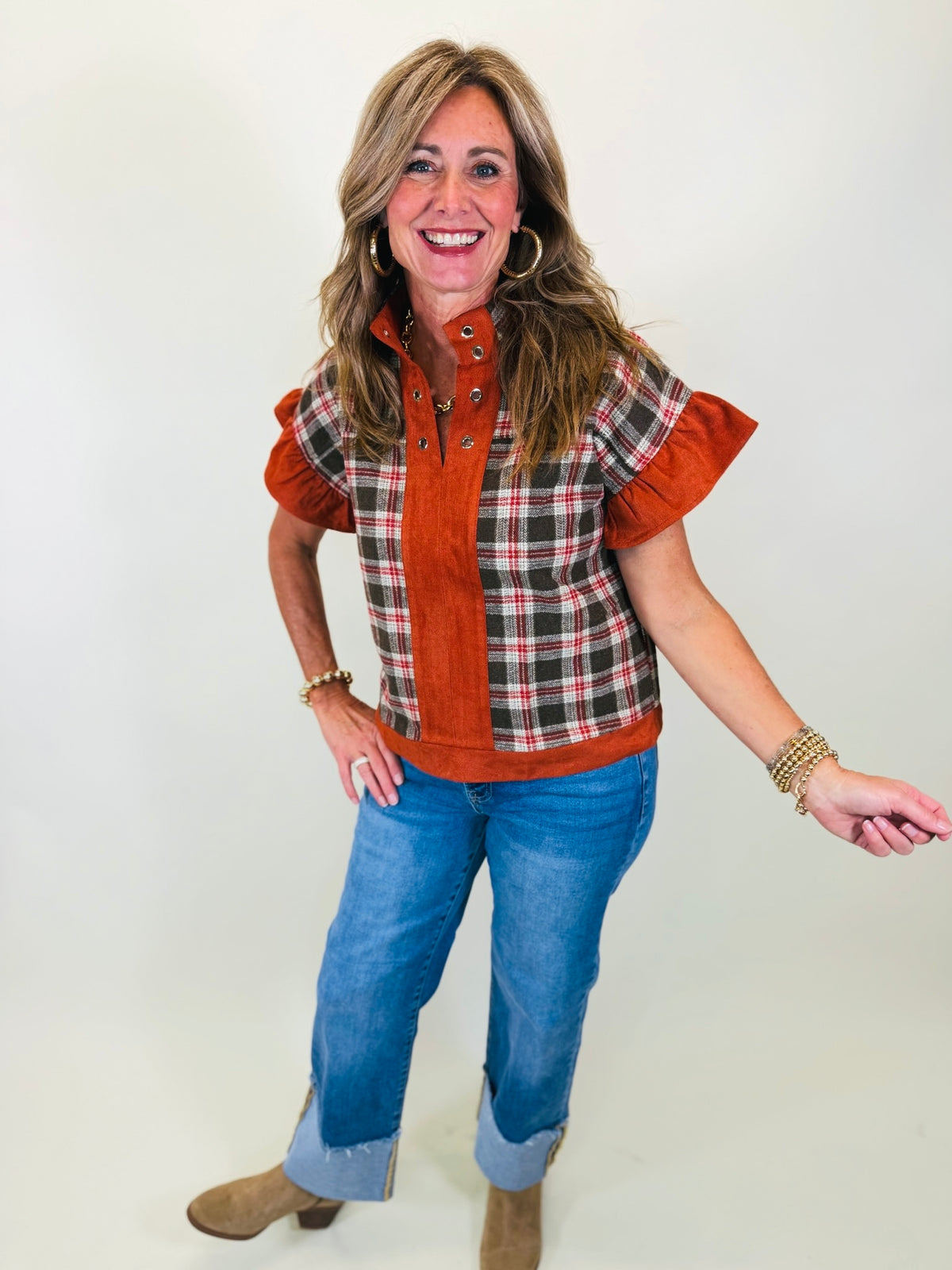 Kelly wearing the Amira rust plaid short-sleeve top with solid rust trim, blue jeans and tan ankle boots.