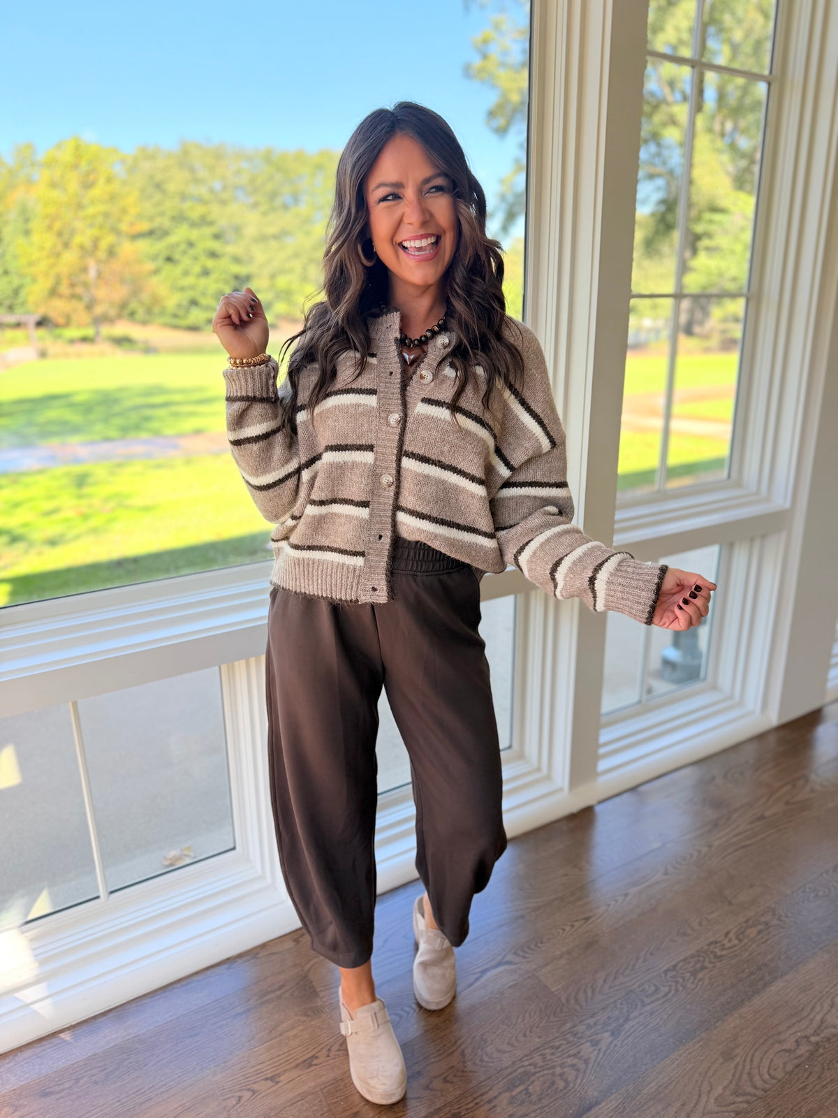 Brooke wearing the Anastasia espresso jogger lounge pants with a beige and brown striped cardigan and cream clogs.