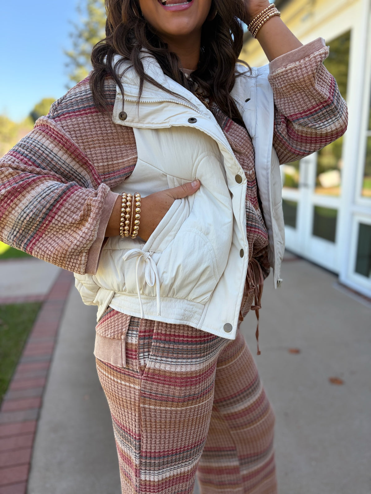 Close-up of the Aurora ivory puffer vest showing its quilted texture, stand collar, front closure and drawstring details.