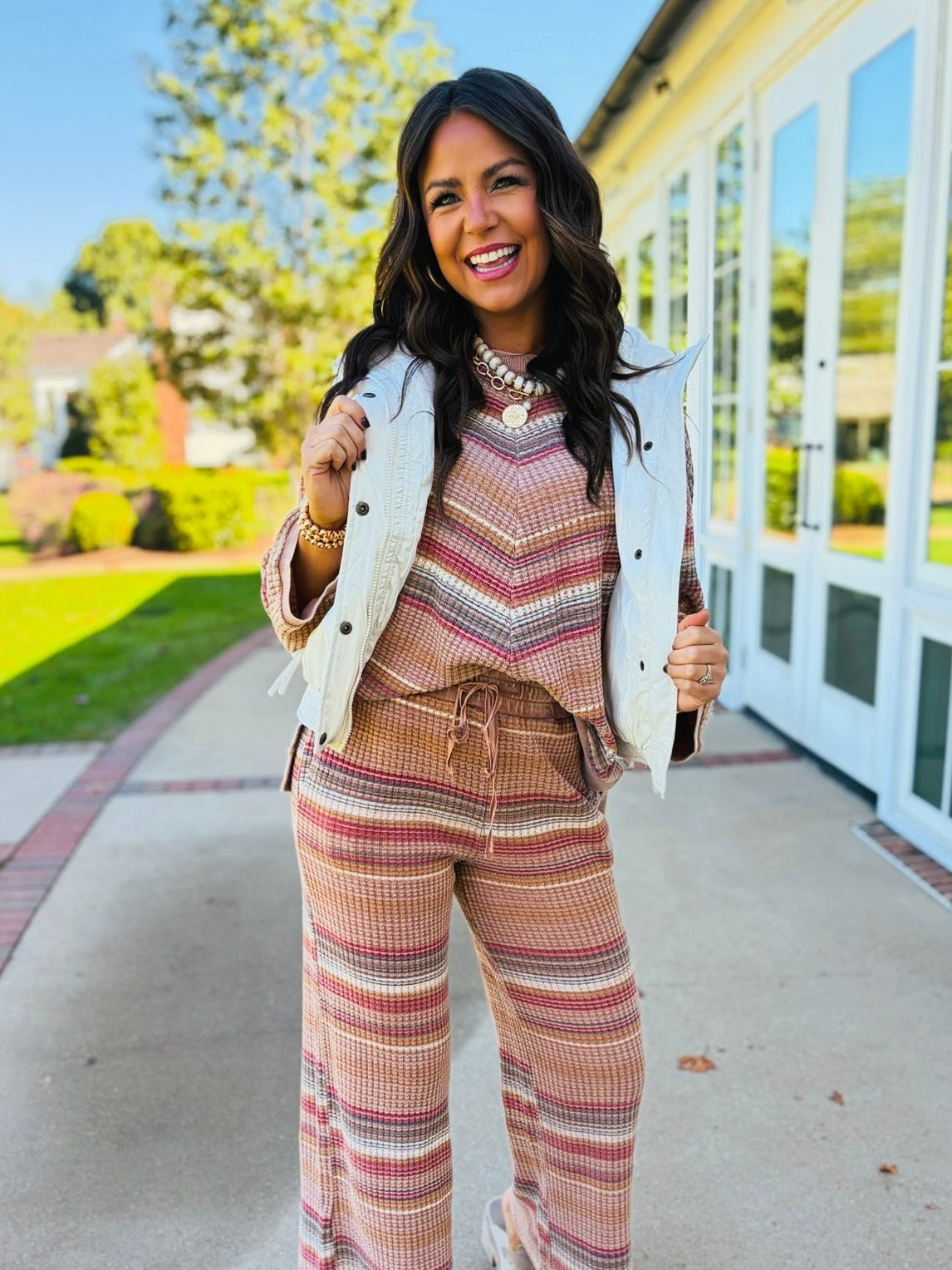 Brooke wearing the Aurora ivory drawstring puffer vest over a coordinating striped knit outfit.