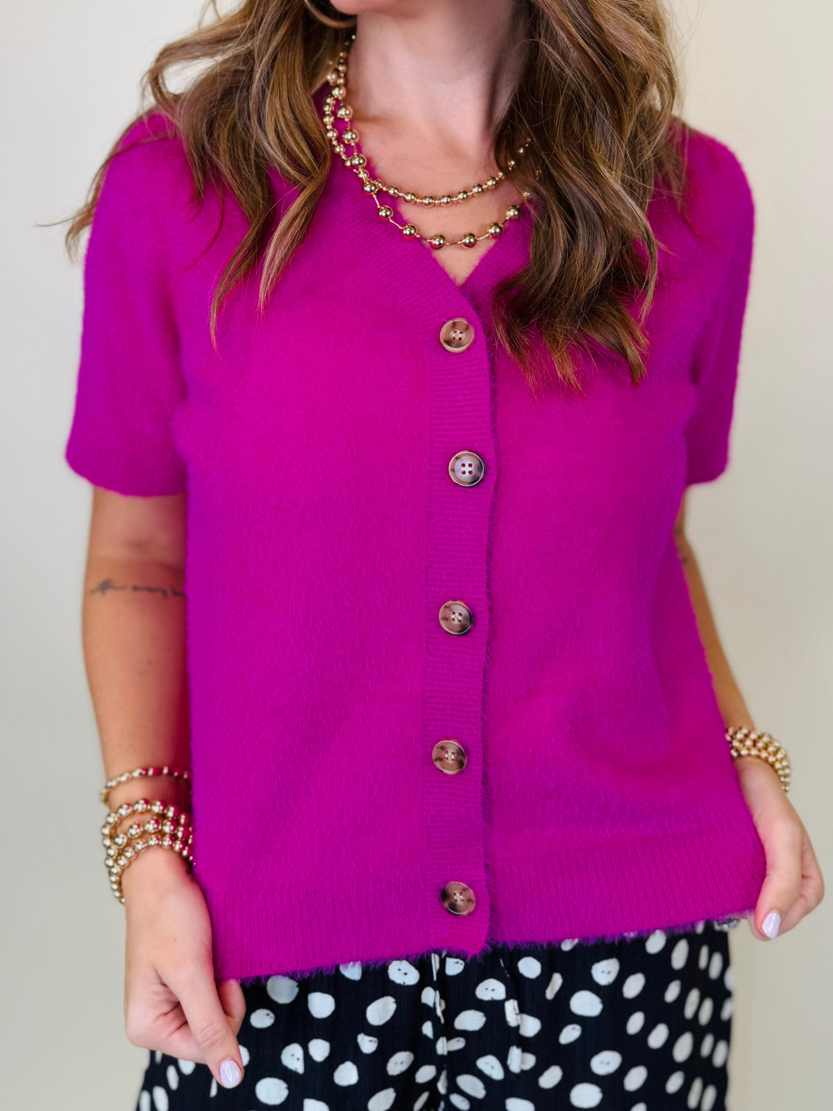 - Close-up of the Charlee magenta sweater showing its fuzzy knit texture, V neckline and button front.