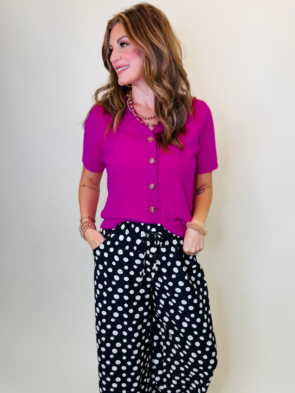 Morgan wearing the Charlee magenta short sleeve button front sweater with black and white printed pants.