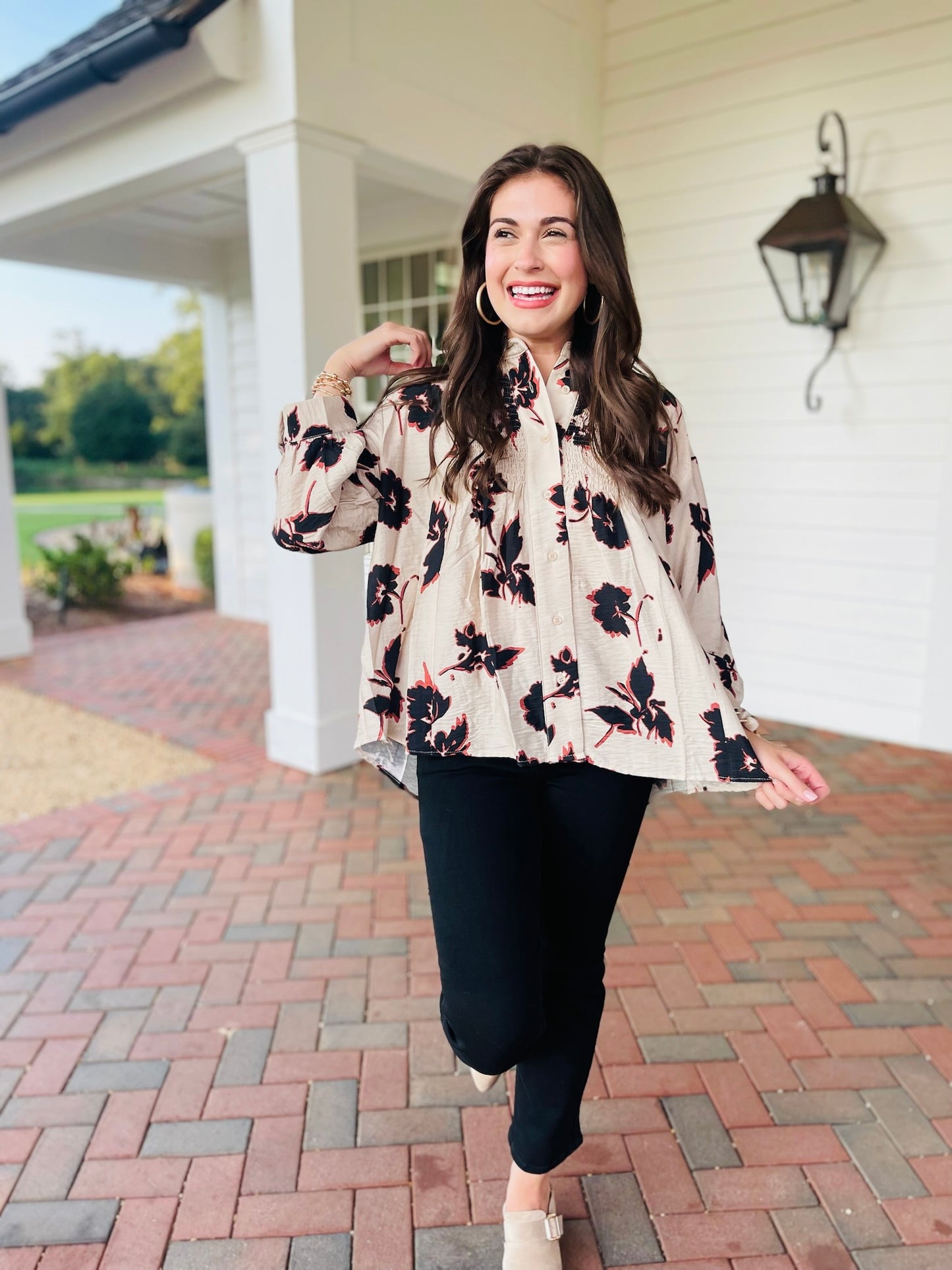 Lacey wearing the Cora ecru and black floral tie-neck blouse with black pants and cream loafers