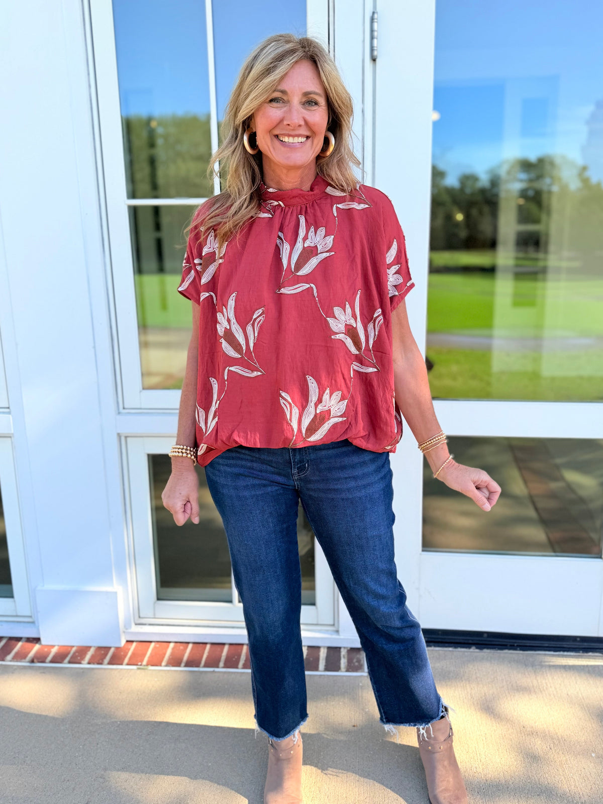 Kelly wearing the Delilah auburn floral tie-back blouse with cropped blue jeans and neutral ankle boots.