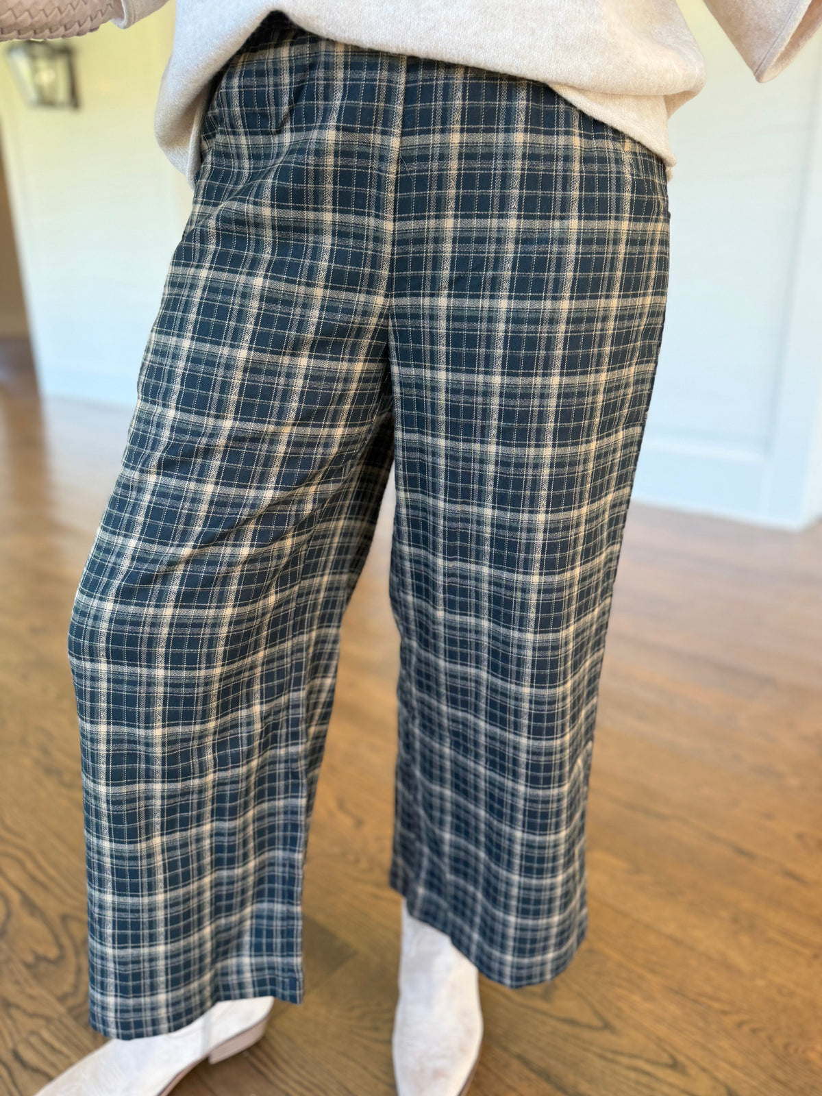 Close-up of the Delphine hunter green plaid wide-leg pants showing their front pockets, plaid pattern and relaxed silhouette.