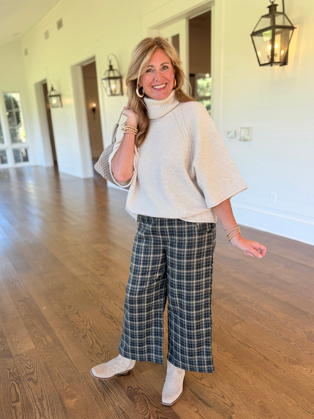 Kelly wearing the Delphine hunter green plaid wide-leg pants with a cream turtleneck sweater and neutral ankle boots.