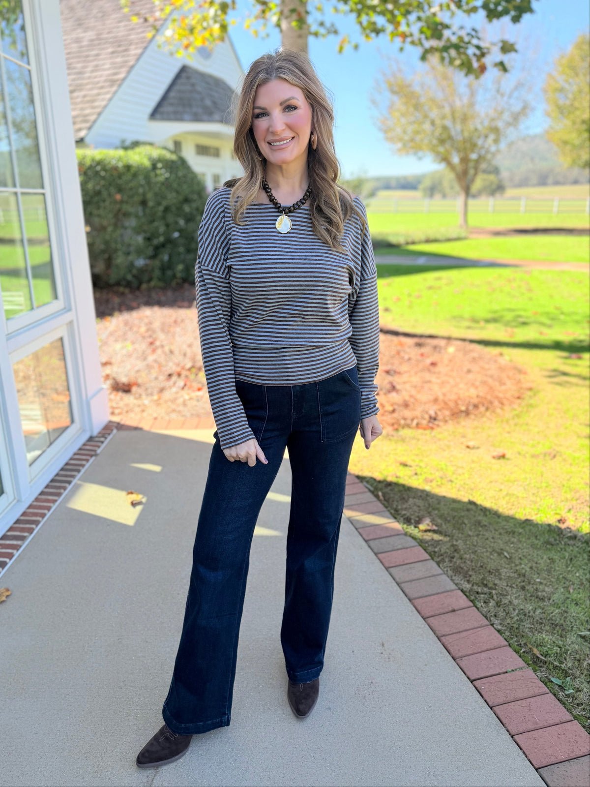 Morgan wearing the Elizabeth chocolate and blue striped boat-neck top with dark flare jeans and ankle boots.