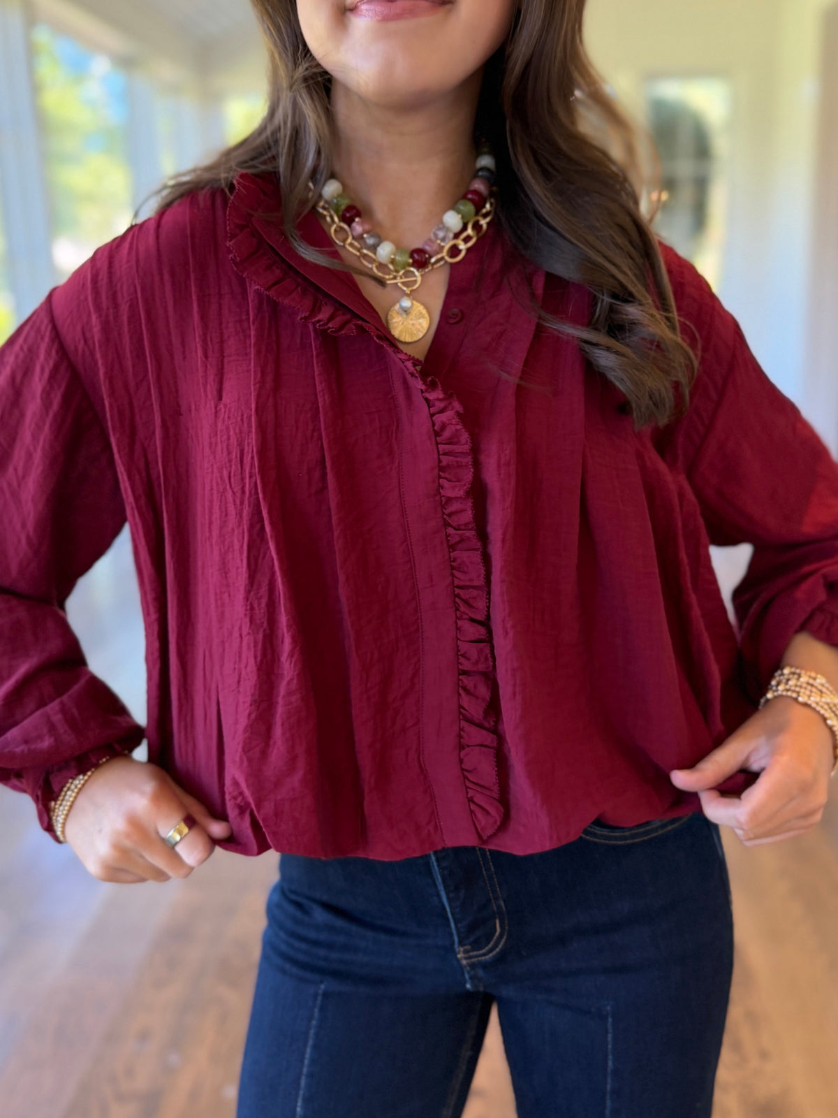 Close-up of the Eloise burgundy blouse showing its ruffle-trimmed split neckline, front detailing and textured fabric.