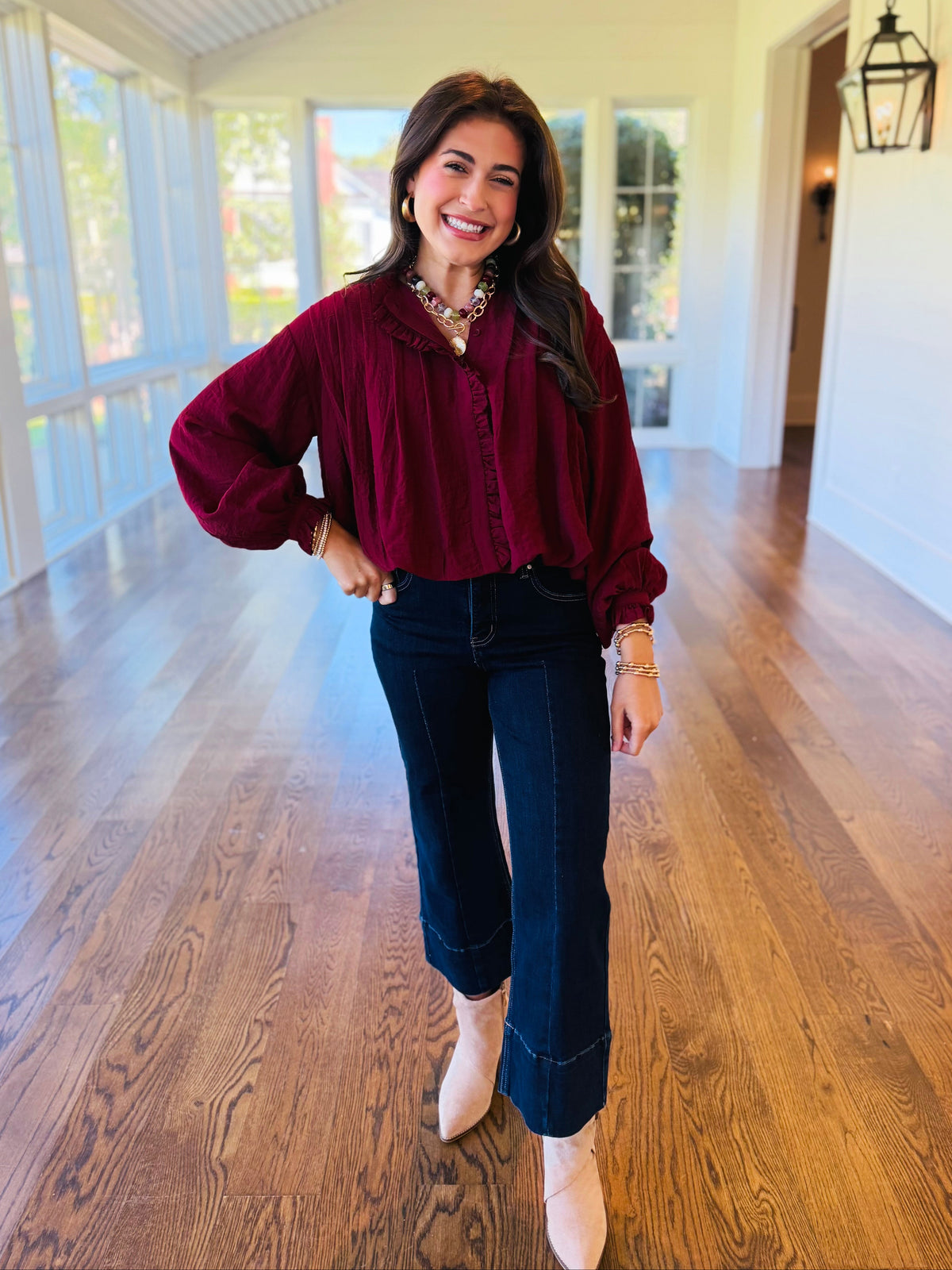 Lacey wearing the Eloise burgundy ruffle trim blouse with dark jeans and neutral ankle boots.