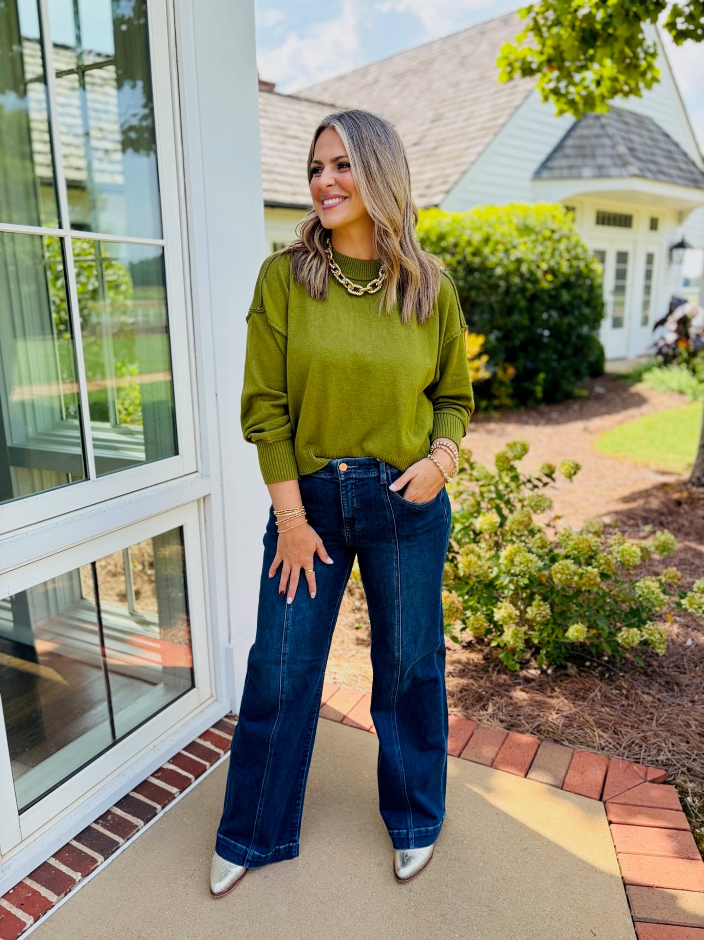 Close-up of Jessica wearing the Emma olive crew-neck sweater with dropped shoulders and ribbed trim