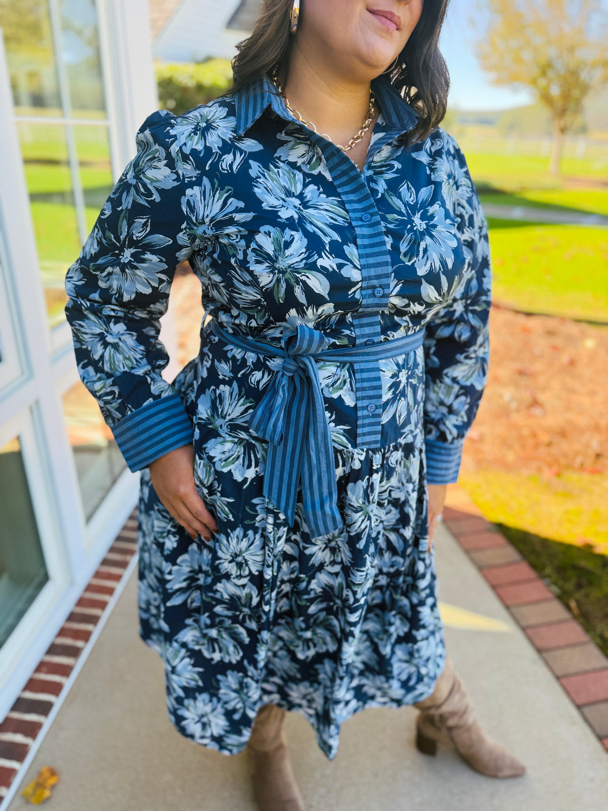 Closer view of the Estelle blue floral midi dress showing its button front, floral print, striped trim and coordinating waist tie.