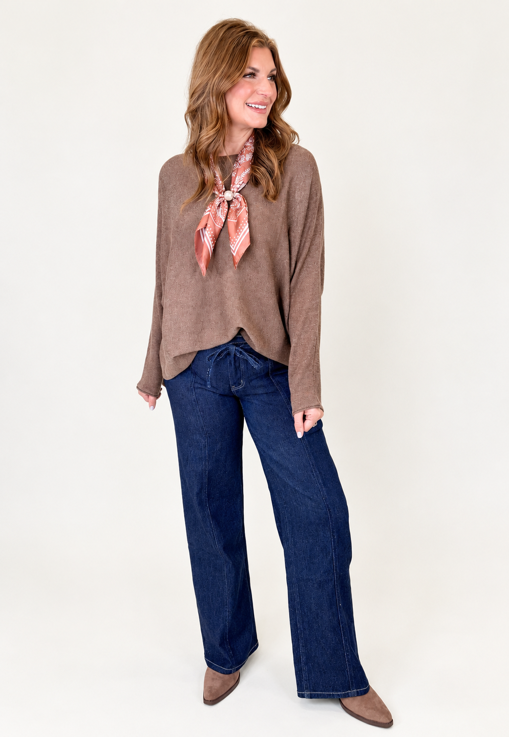 Morgan wearing the Finley mocha relaxed knit top with dark blue wide-leg jeans, a printed neck scarf and brown pointed-toe flats.