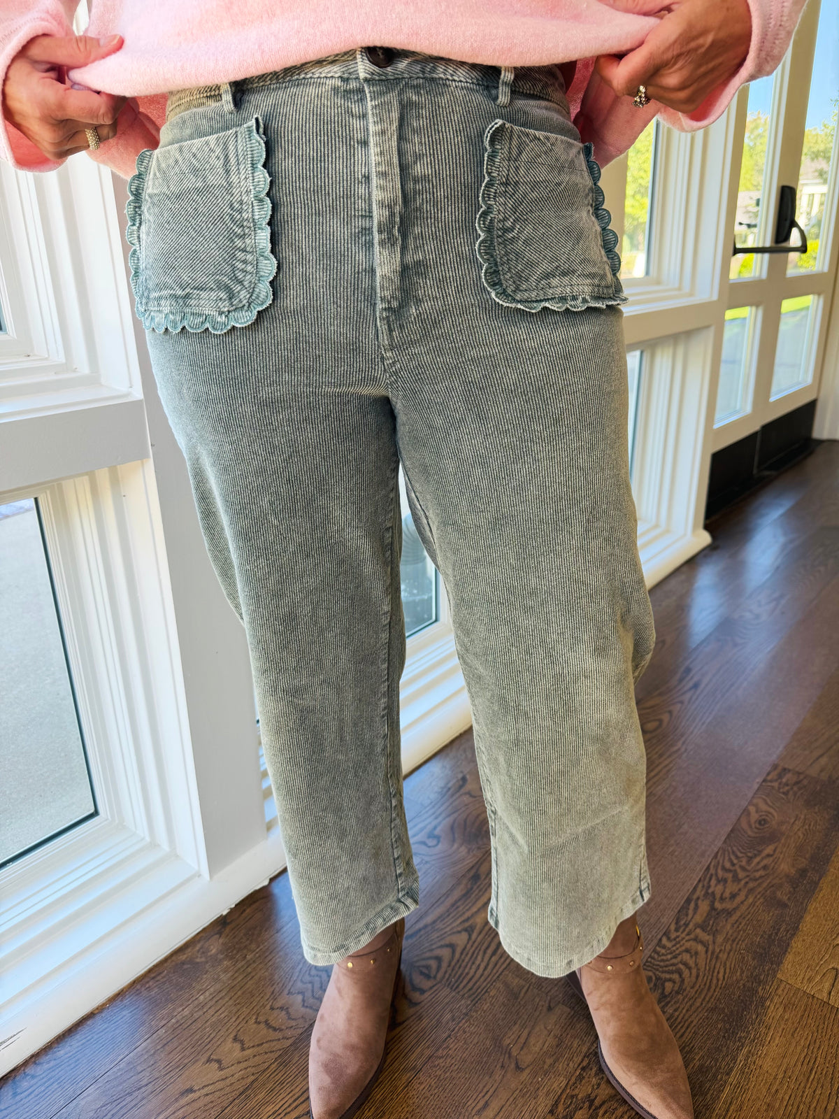 Close-up of the Greer Pacific green corduroy pants showing the high-rise waist and scallop-trimmed patch pockets.