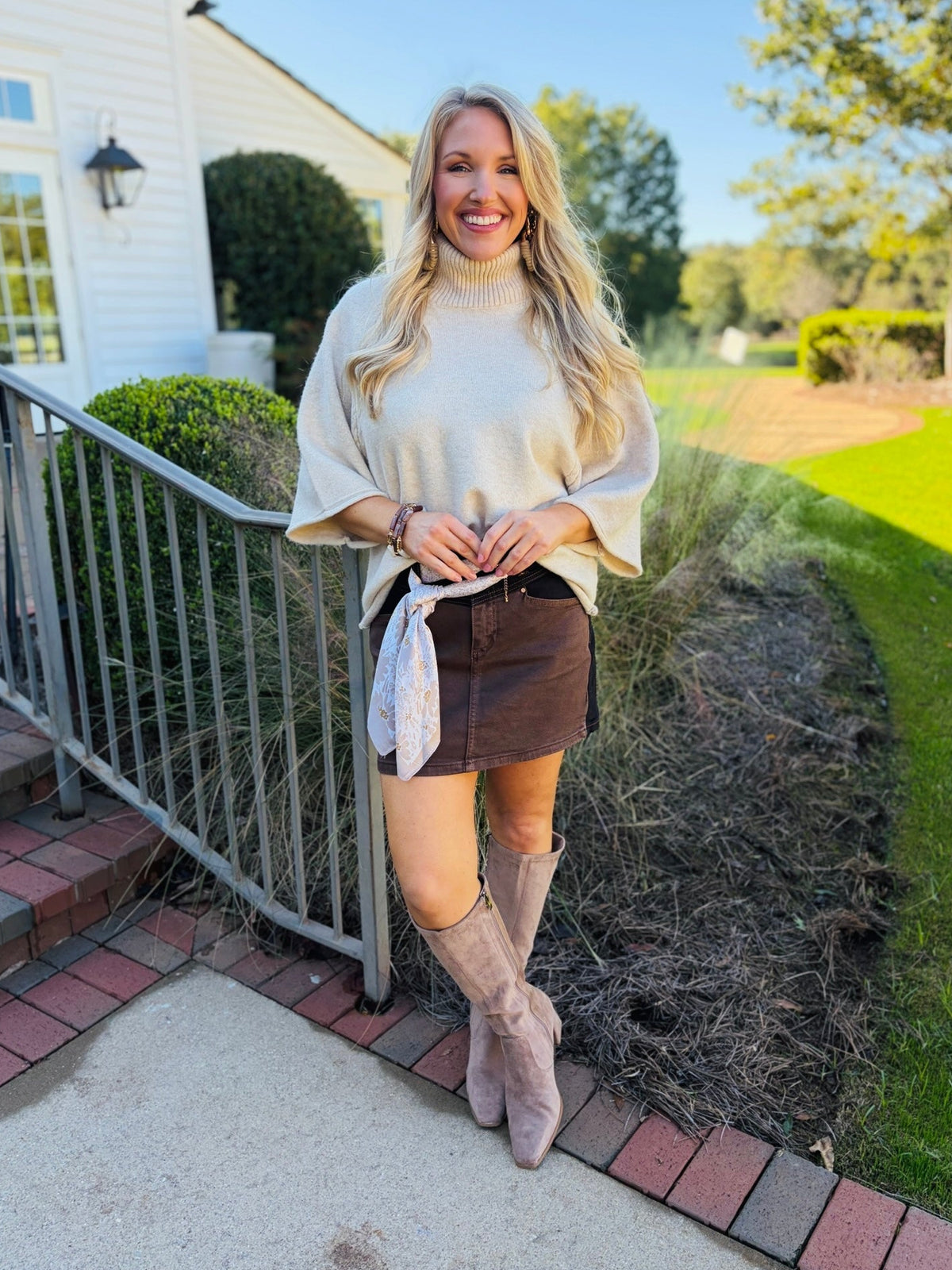 Lorin wearing the Hadley black and brown colorblock mini skirt with a cream turtleneck sweater and taupe boots.