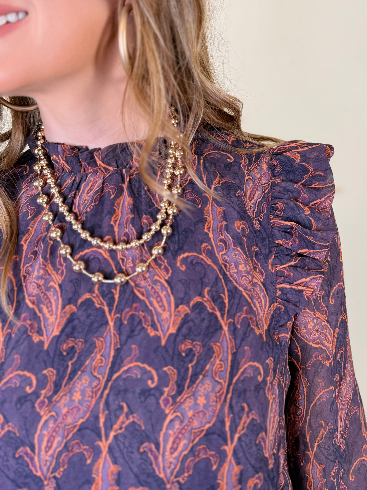 Close-up of the Josephine dress showing its eggplant paisley print, high neckline and ruffled shoulders.