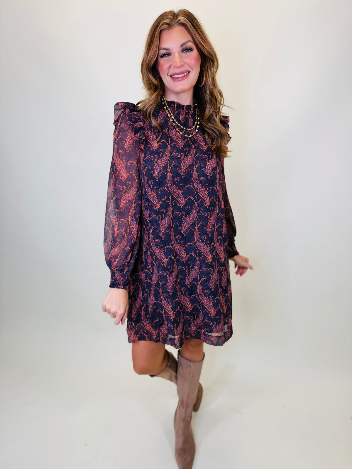 Morgan wearing the Josephine eggplant paisley ruffle mini dress with taupe knee-high boots.