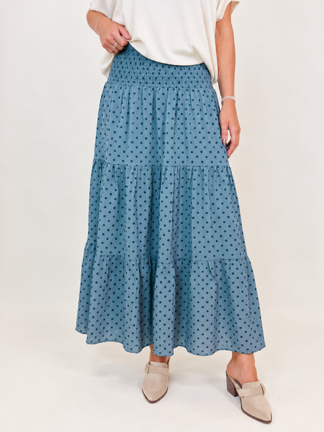 Close-up of the Katie mint green maxi skirt showing its smocked waistband, dark polka-dot print and gathered tier construction.